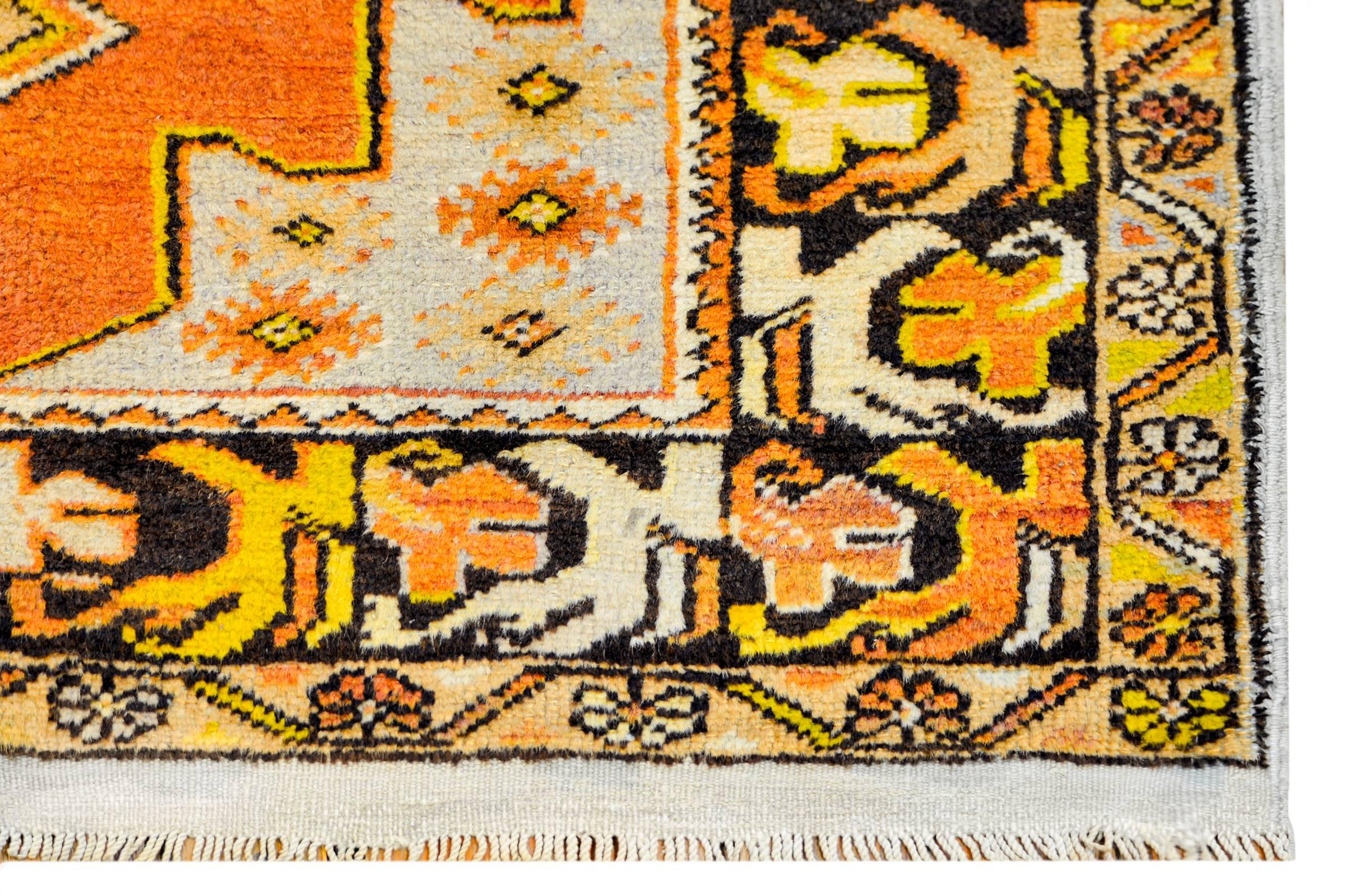 A vintage Turkish Oushak rug with a beautiful pattern woven in orange, gold, brown, and cream colored wool. The border is exceptional, with large-scale wide stylized floral and leaf patterned stripe flanked by a petite floral and vine pattern.