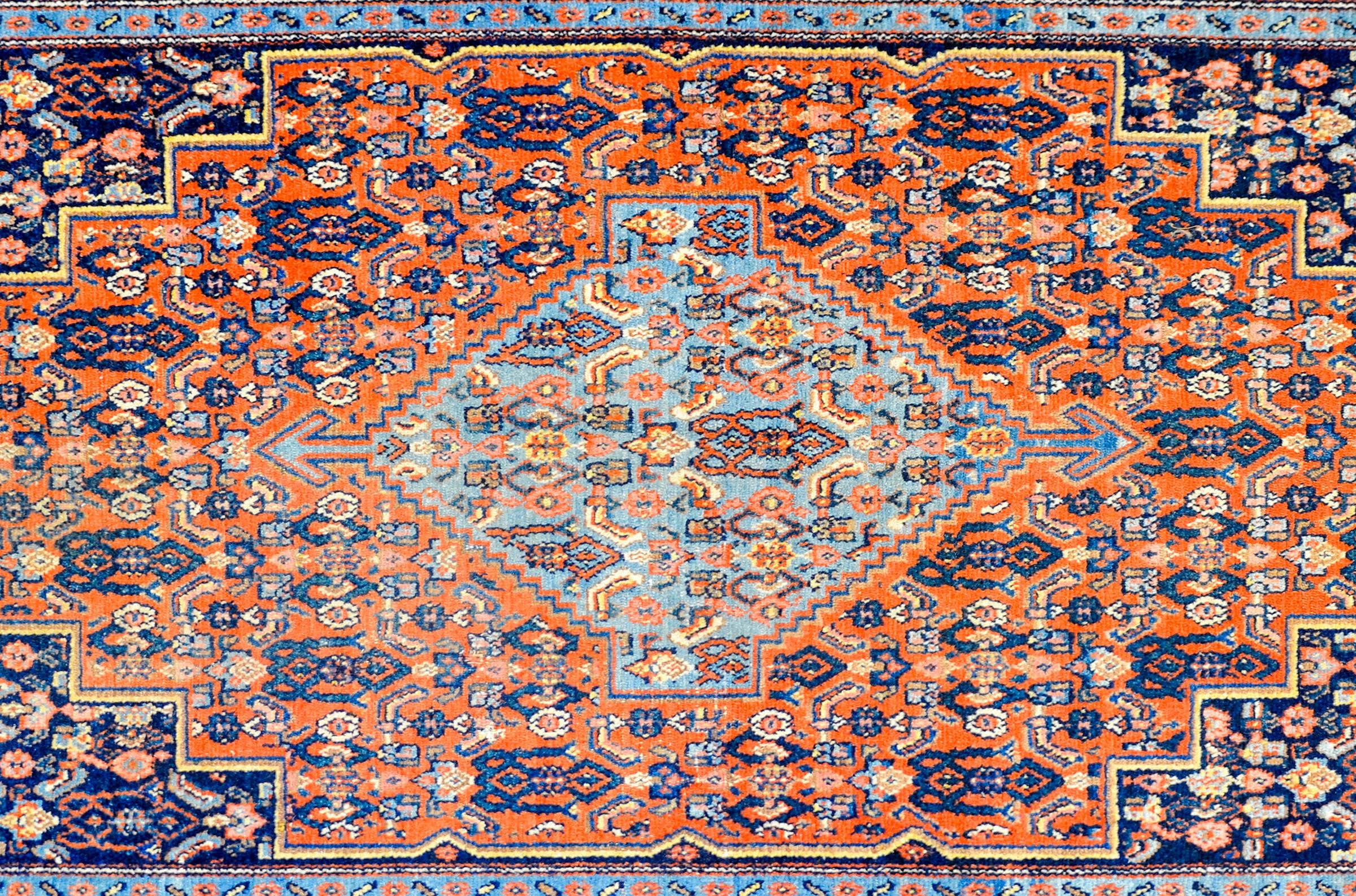 A beautiful early 20th century Persian Seneh rug with a wonderful diamond medallion woven with an all-over multicolored trellised floral pattern, on a light indigo background, amidst a field woven with a matching trellised floral pattern as the