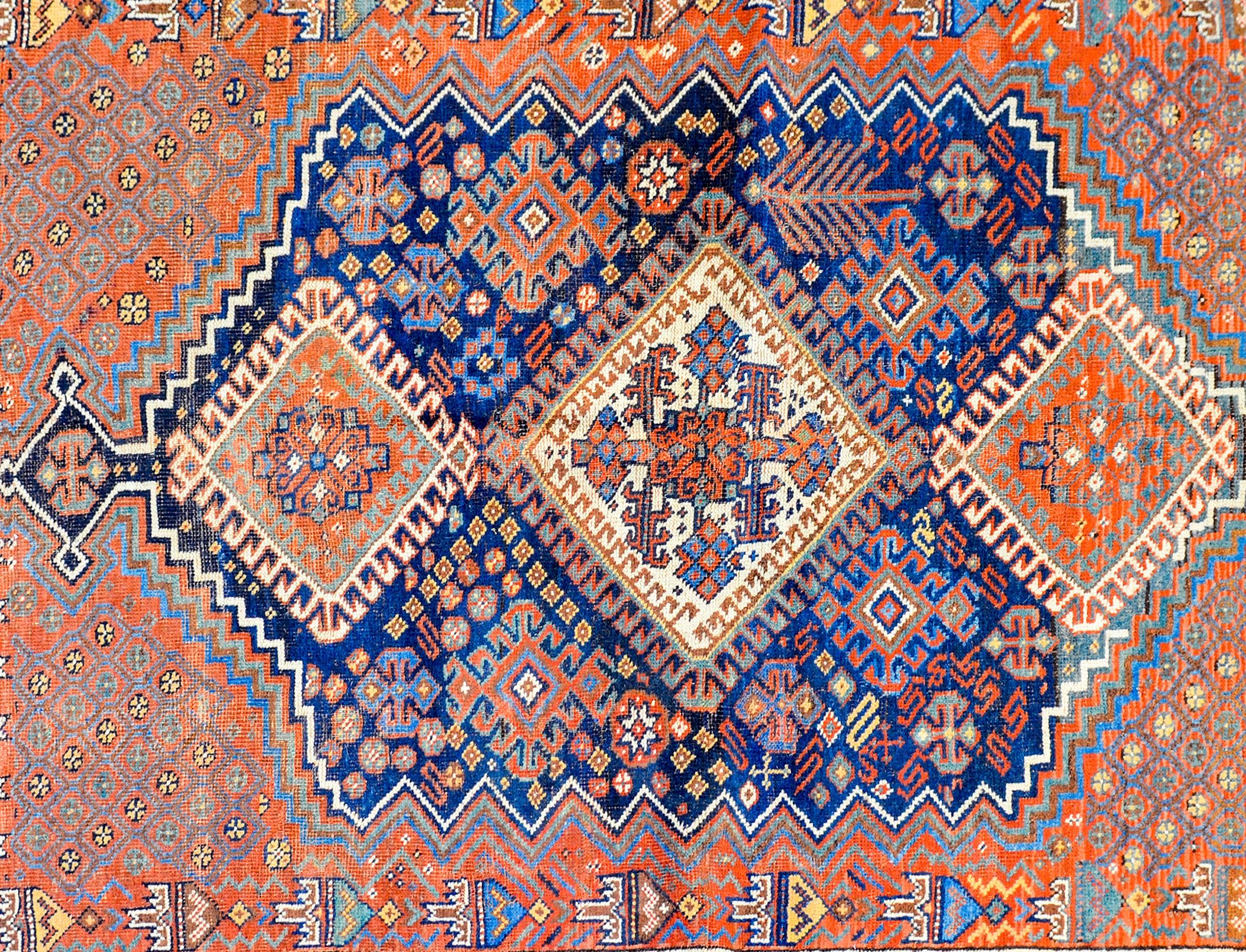 An incredible early 20th century Persian Ghashghaei rug with three large multicolored diamond medallions amidst a fantastic field of stylized flowers and bushes, trees-of-life all on a dark indigo background. The border is masterfully rendered, with