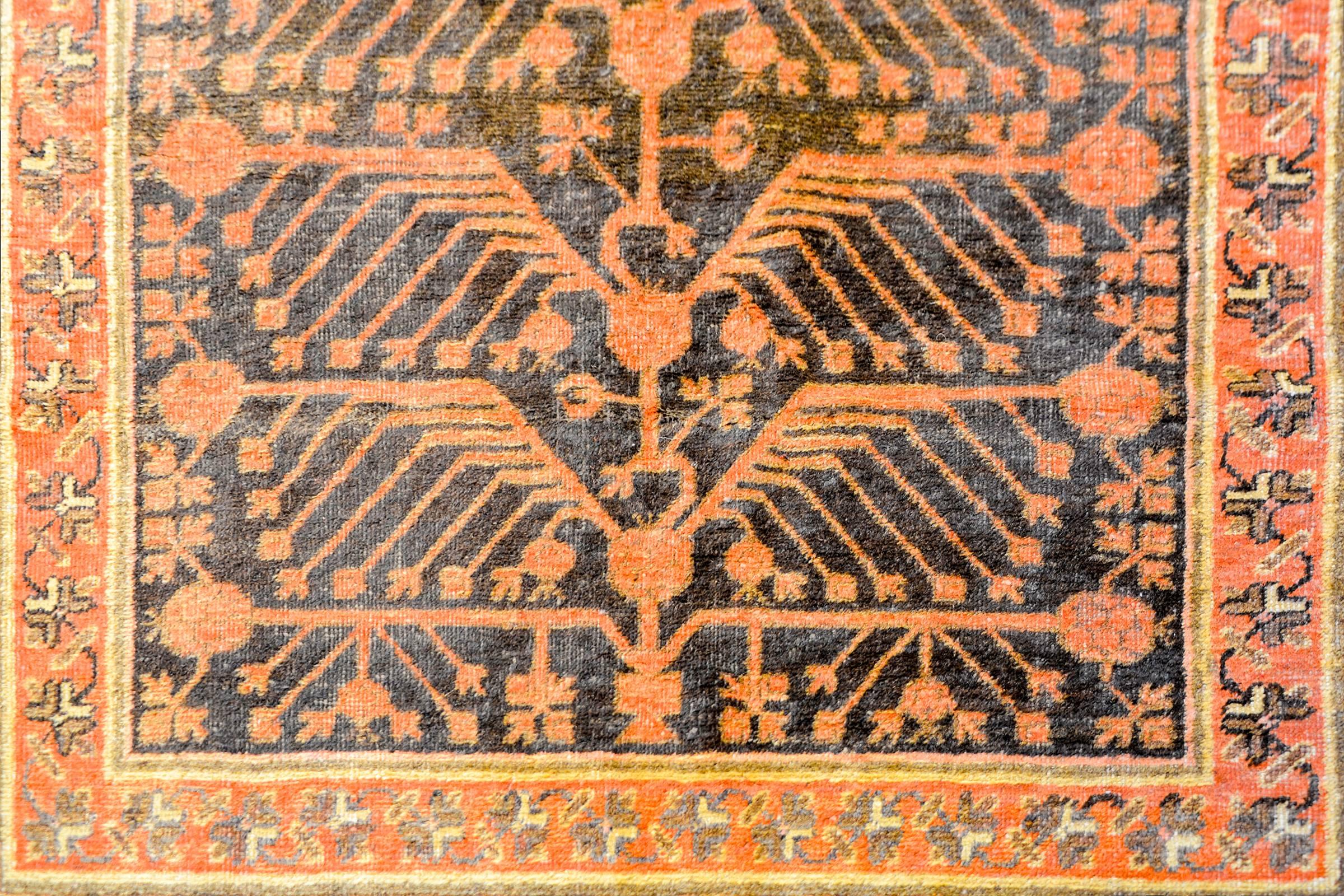Ein unglaublicher zentralasiatischer Khotan-Teppich aus den frühen 1940er Jahren mit einem einzigartigen, spiegelnden, karminroten Lebensbaum- und Granatapfelmuster auf einem braunen Hintergrund. Die Umrandung ist komplex und besteht aus zwei