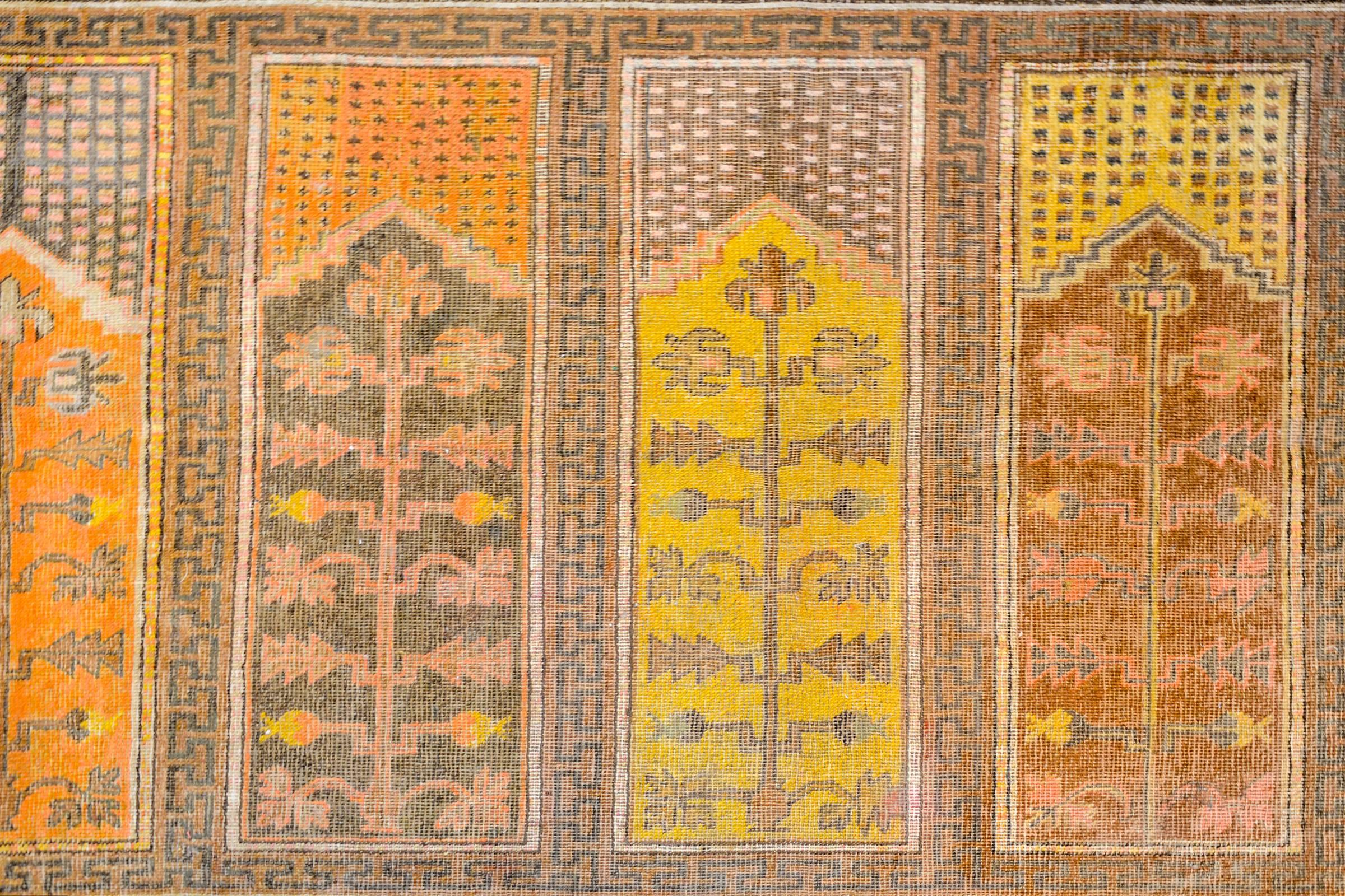 A unique early 20th century Central Asian pictorial Khotan rug with six panels, each depicting a blossoming tree woven in a different color of vegetable dyed wool. The border is fantastic with an inner stripe containing Chinese Shou characters, and