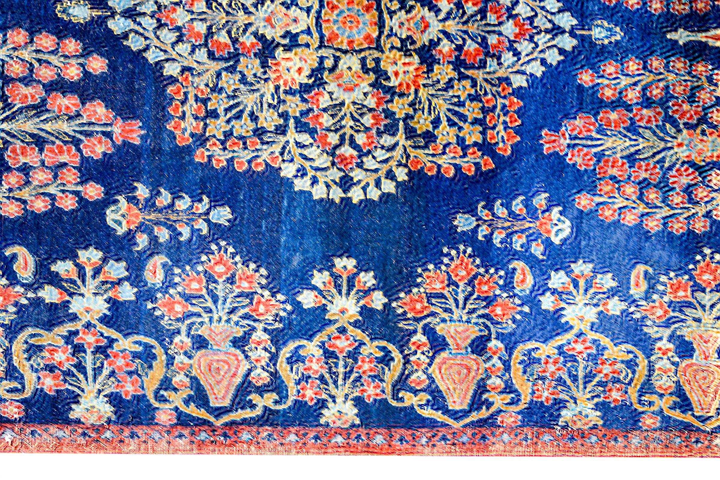 A wonderful early 20th century Persian Kirman rug with a densely woven mirrored floral and leaf pattern woven in indigo, pink, gold and crimson vegetable dyed wool. The border is interesting as it is included in the overall design of the rug, and