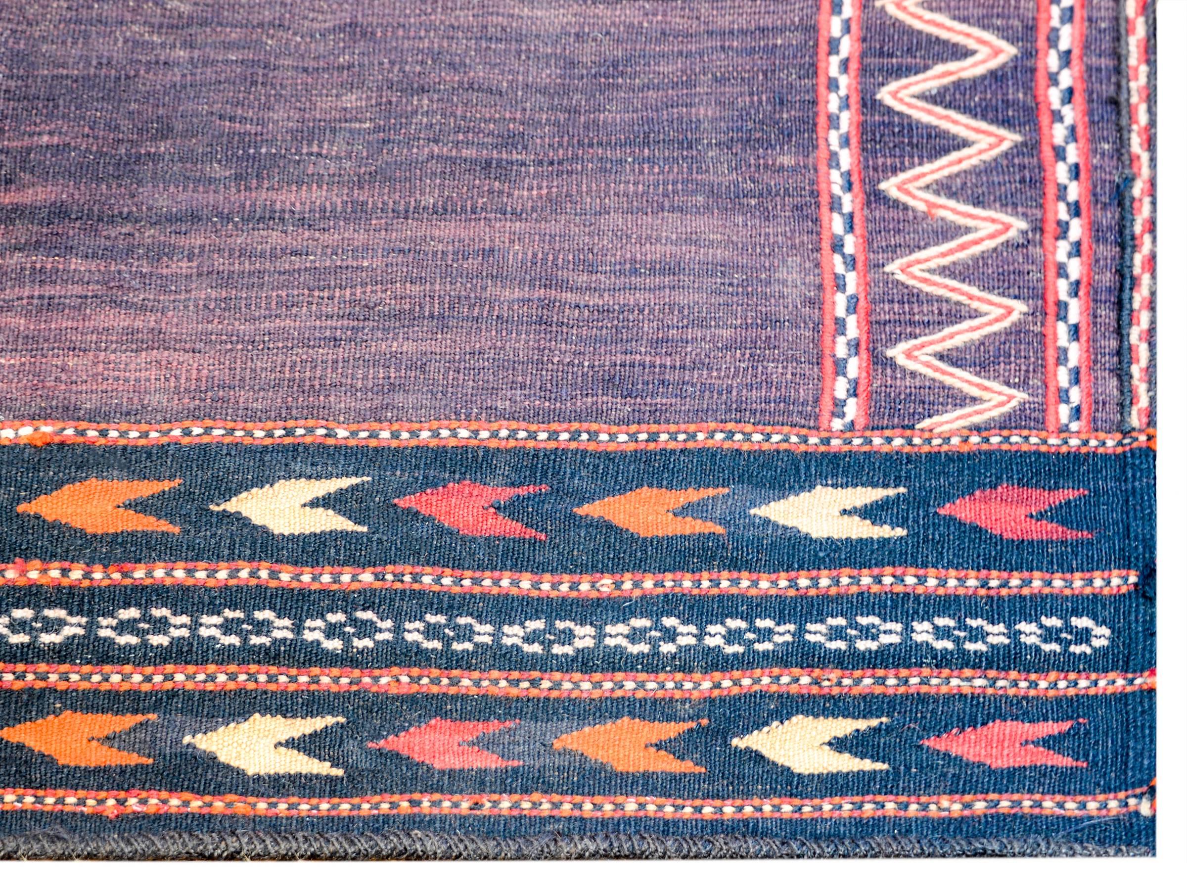 A beautiful early 20th century Baluch Sofreh with a beautiful abrash undyed wool field surrounded by two different zigzag and stripe borders woven in crimson, orange, and natural cream colored wool.