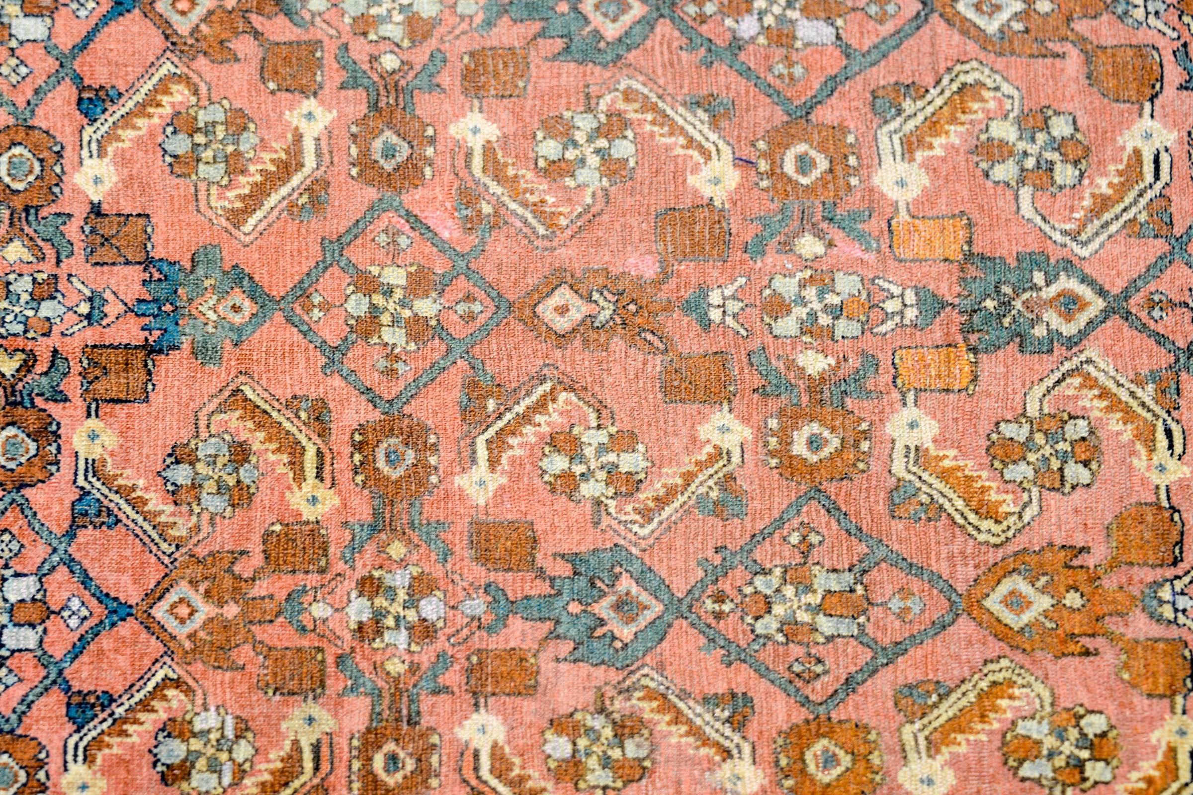 A late 19th century Persian Malayer rug with all-over multicolored trellised floral and vine pattern woven in indigo, crimson, and cream colored wool, on a coral colored background. The border is composed with one central floral stripe on an indigo