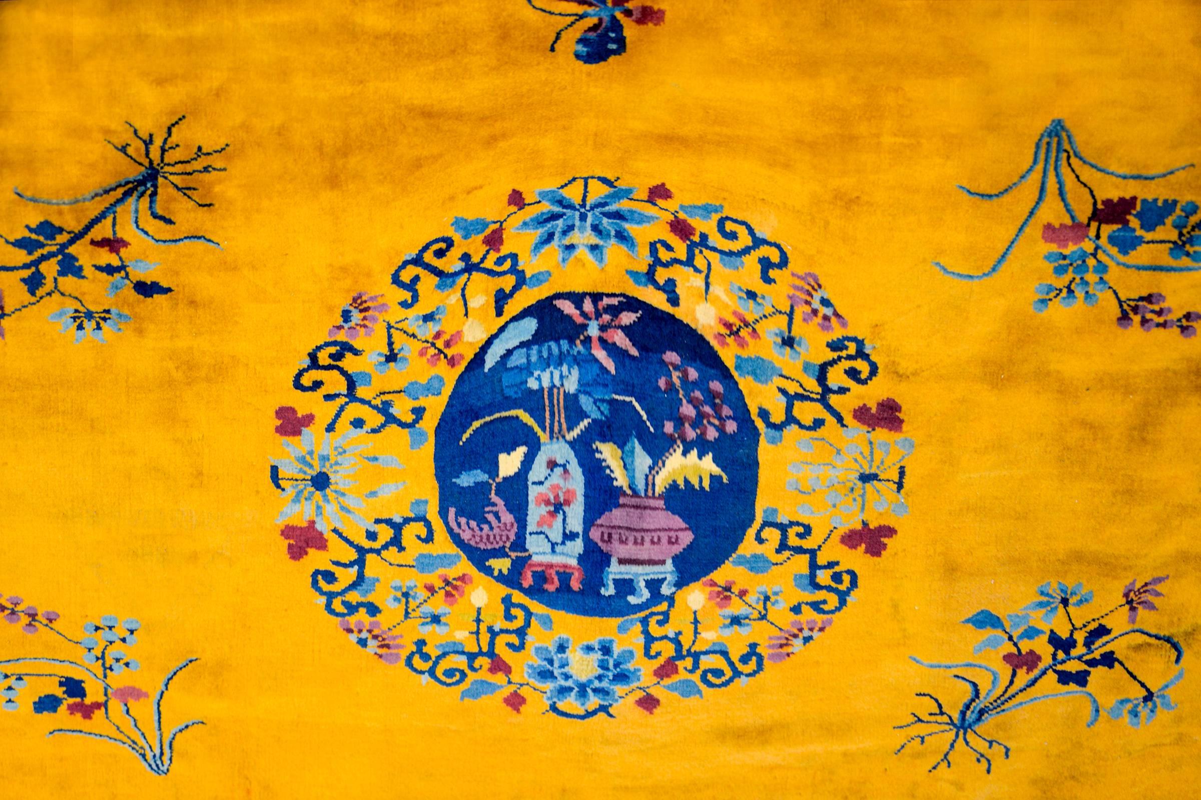 A brilliant early 20th century Chinese Art Deco rug with a fantastic and bold gold central field, surrounded by a wide richly hued indigo border. A central circular medallion features two vases potted with auspicious flowering lotus and cherry