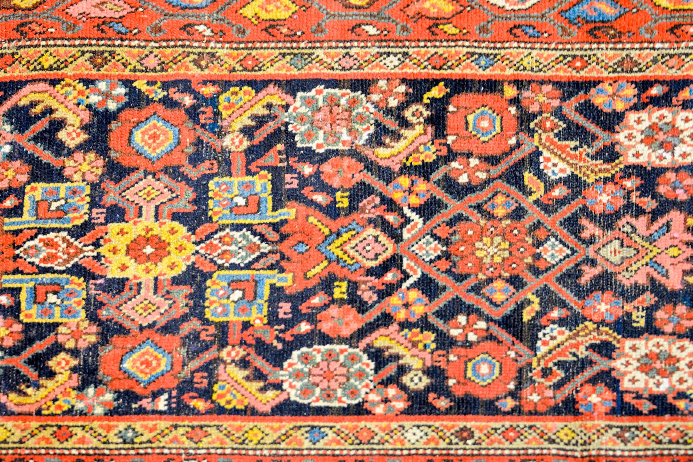Magnifique tapis de course Persan Malayer du début du 20ème siècle, avec un motif floral et de vigne multicolore en treillis, tissé en laine de couleur indigo, cramoisi, or et crème, sur un fond indigo foncé. La bordure est composée de quatre motifs