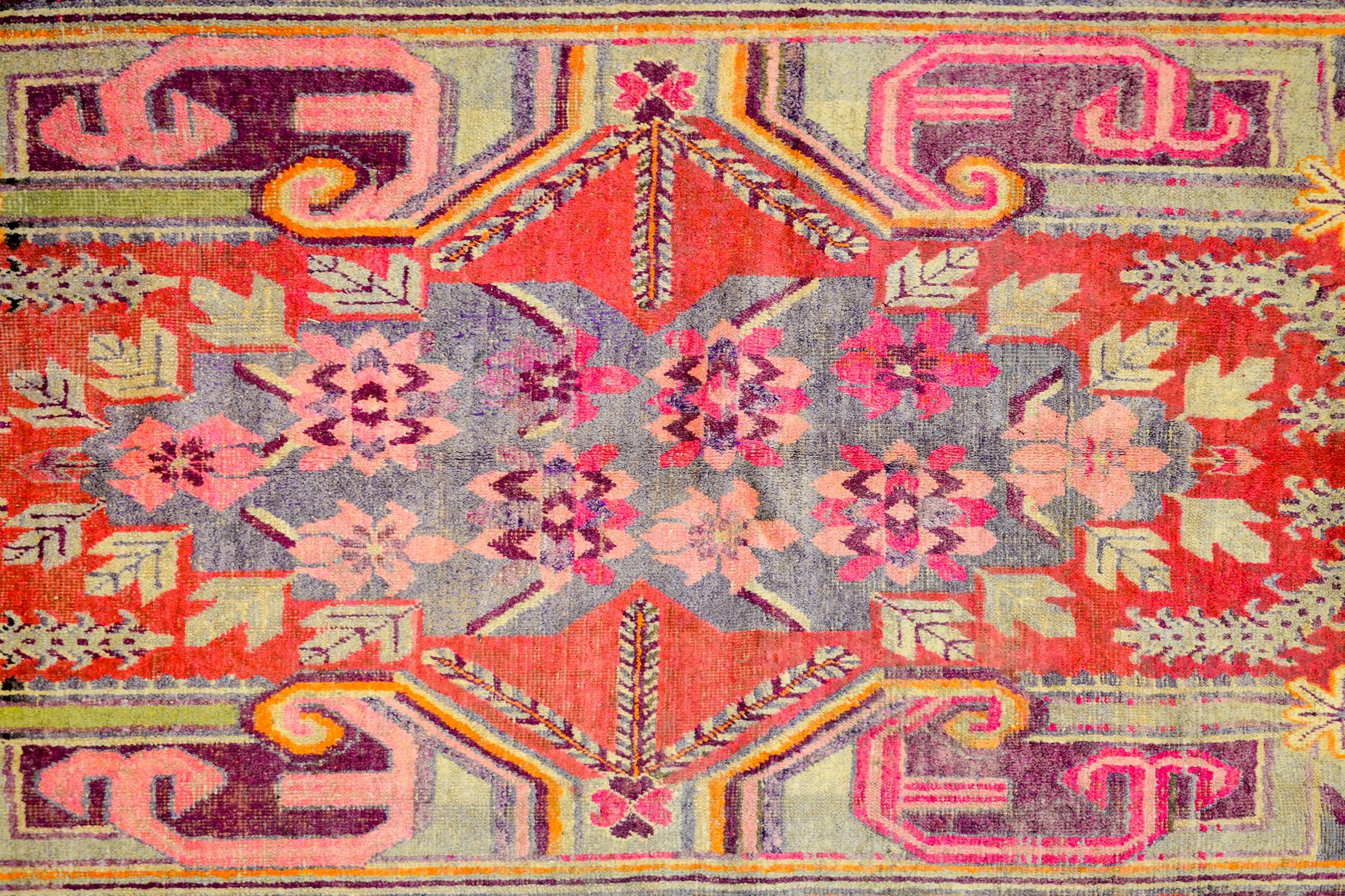 A wonderful early 20th century Central Asian Samarkand rug with an incredible asymmetrical large-scale floral medallion woven in crimson, violet, pink, black, and cream colored wool. The medallion lives amidst a crimson field with flowering branches