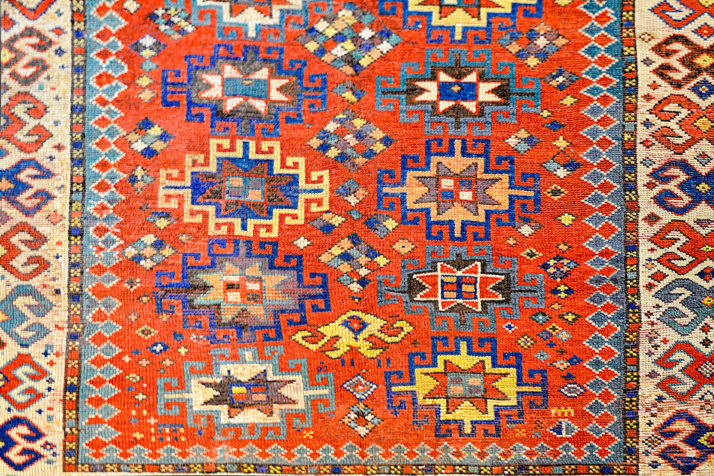 An outstanding early 20th century Lambalo, Caucasus Kazak rug with a beautiful crimson central field containing multiple geometric medallions woven in indigo, green, gold, and brown vegetable dyed wool. The border is wide, with a geometric form