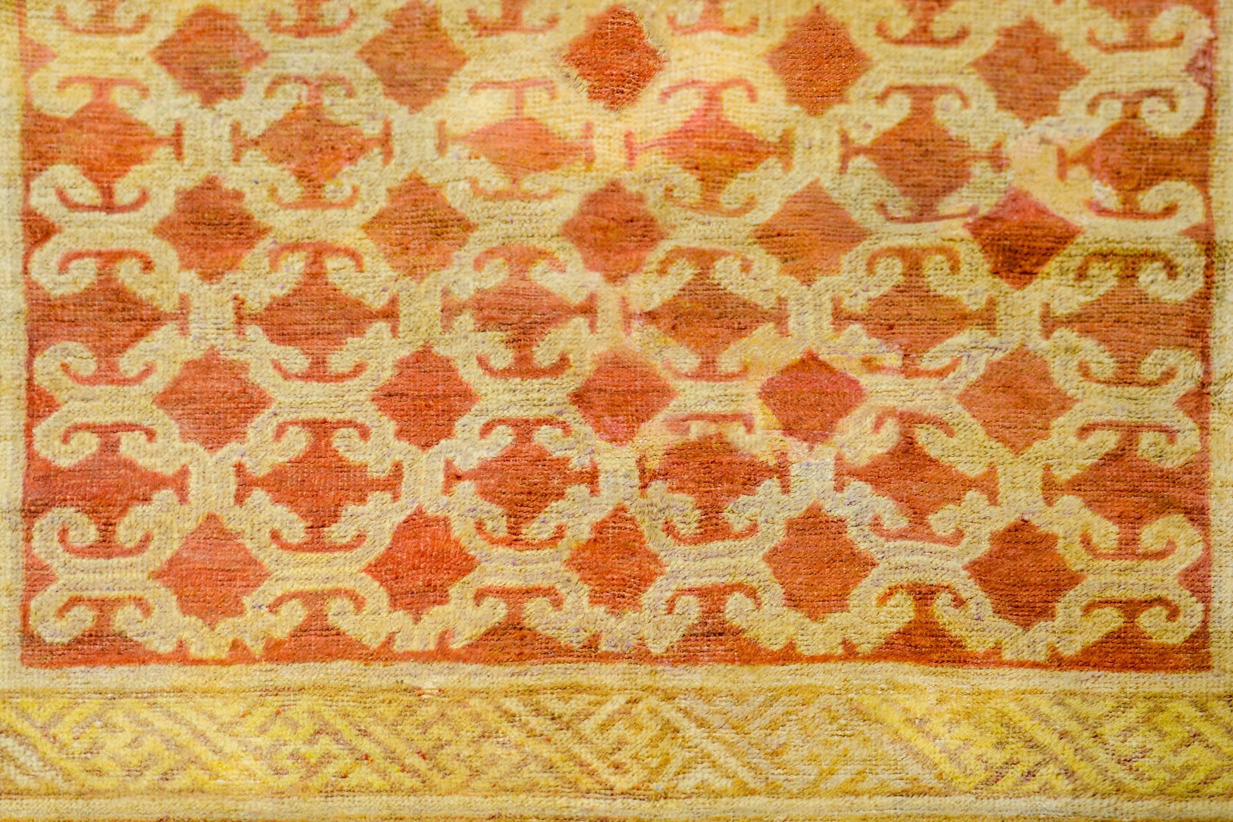 An unusual early 20th century Central Asian Khotan rug with a knotted lattice pattern woven in a cream colored wool on a burnt orange background. The border in composed with two patterns, the inner stripe being a Buddhist meandering motif, and the