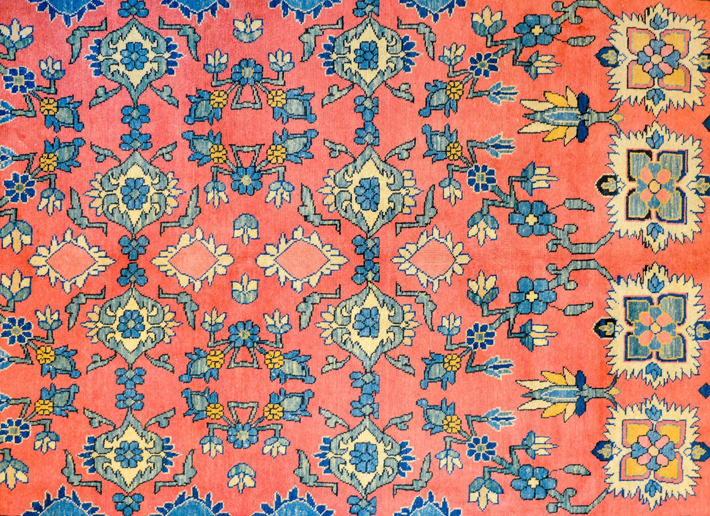 Un audacieux tapis persan Meshkabad de la fin du 20e siècle avec un merveilleux motif floral et de feuilles en treillis à grande échelle tissé en indigo, vert et or, sur un riche fond corail entouré d'une bordure élaborée de fleurs et de vignes