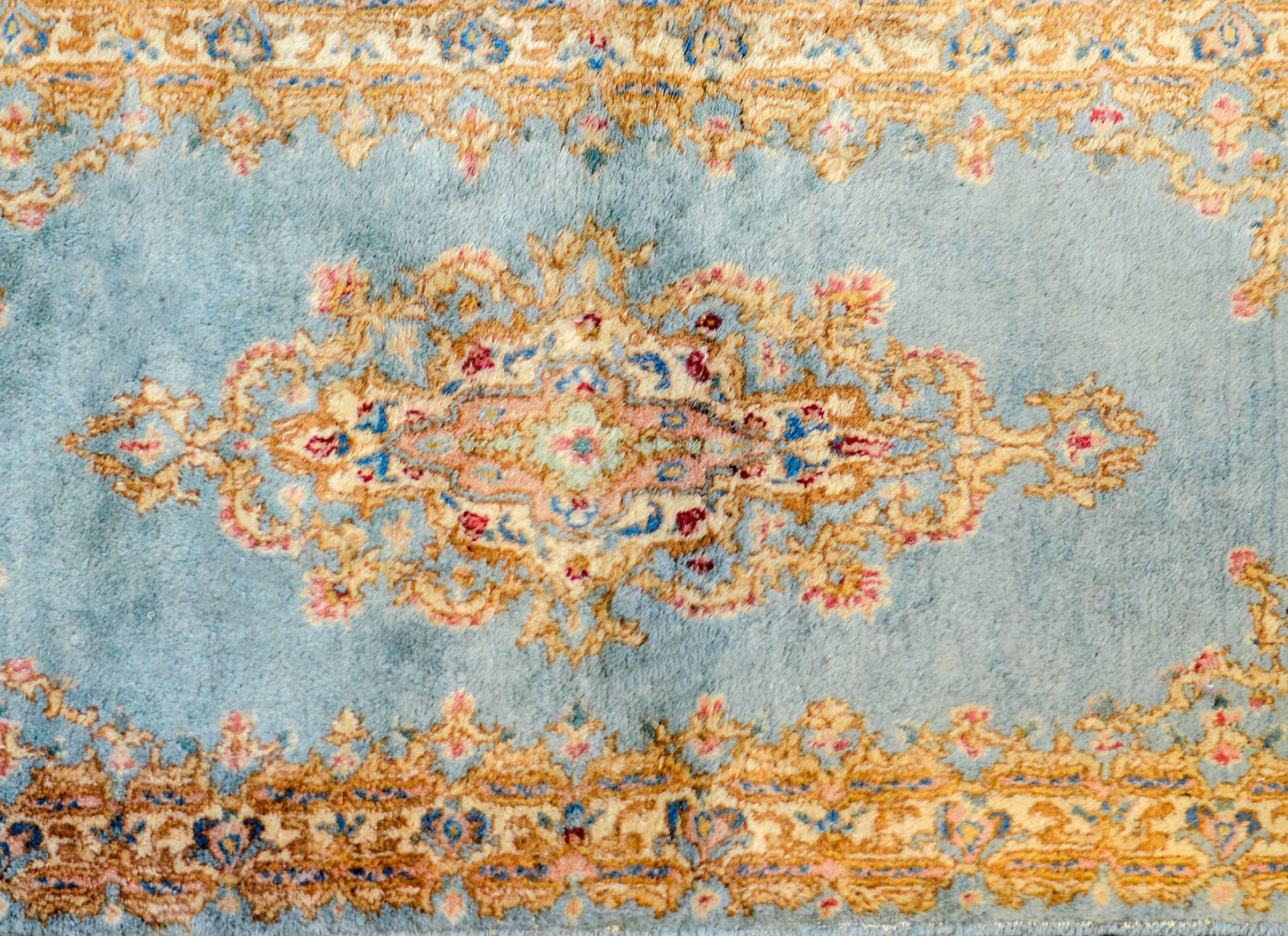 An amazing vintage Persian Kirman rug with woven with an incredible high quality shimmering silky indigo and gold vegetable dyed wool with a large diamond form floral medallion. The border is fantastic with an intensely woven baroque floral border.