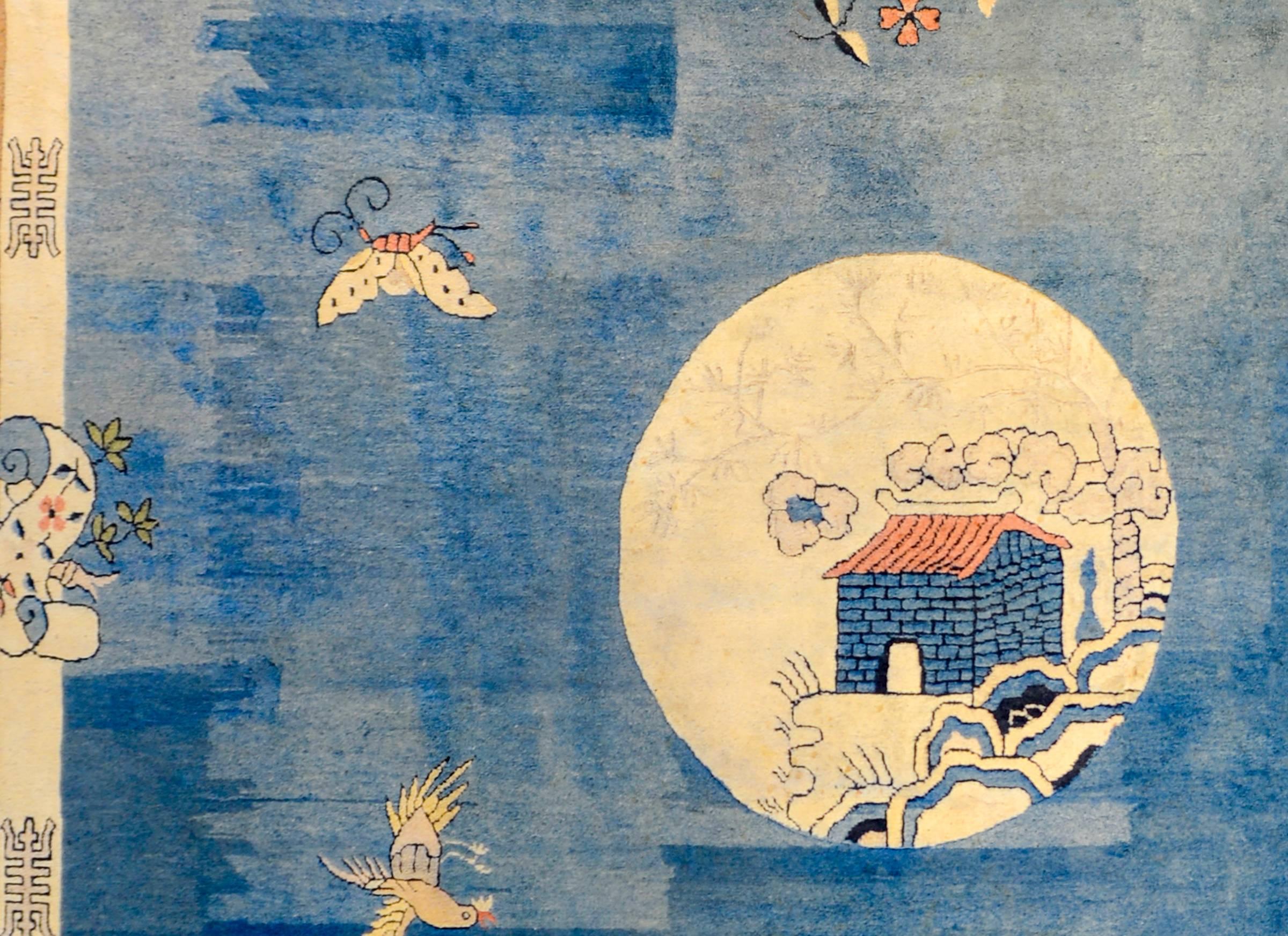 An extraordinary Chinese Peking rug with an amazing abrash indigo central field with butterflies, phoenix, and plumes of incense smoke around a central moon shaped medallion with a garden pavilion in the center. The borer is wide, with two taupe