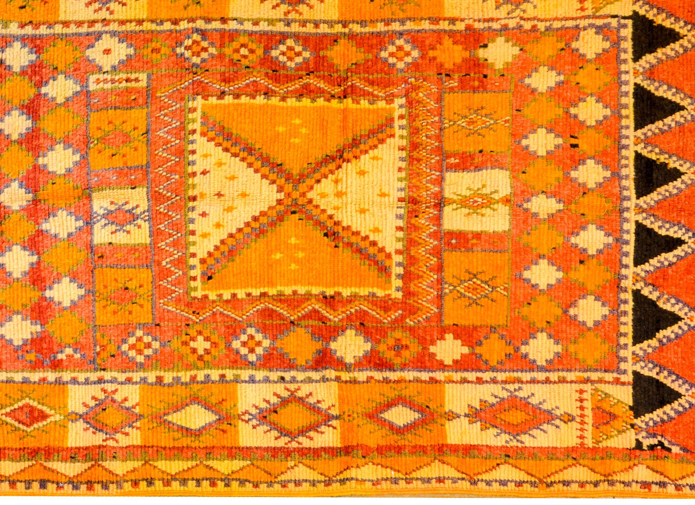 A wonderful brilliantly colored vintage Moroccan runner with an all-over geometric pattern of triangles and diamonds woven in crimson, orange, gold, and hints of violet. The border is complimentary with a similar pattern woven in similar colors.
