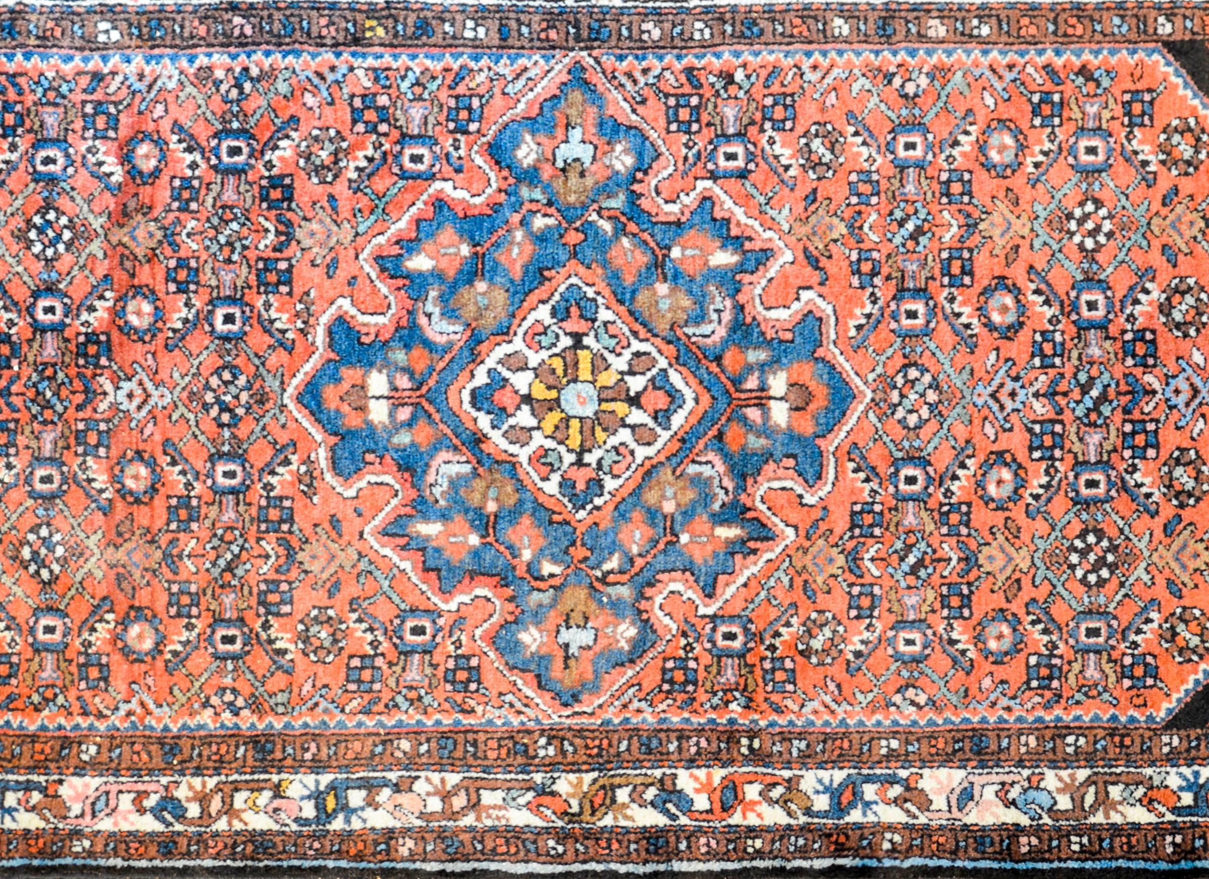 A gorgeous early 20th century Persian Malayar rug with a beautiful central diamond medallion with a an all-over floral pattern. The medallion is surrounded by field of all-over trellis floral pattern woven in indigo and pink, on a crimson