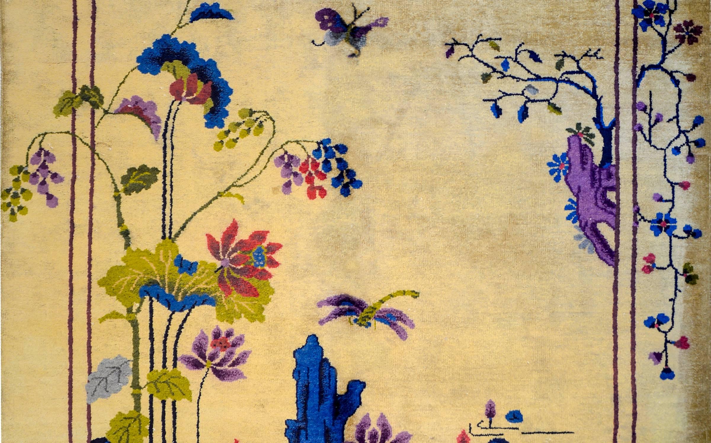 A whimsical early 20th century Chinese Art Deco rug with a beautiful natural champagne colored wool with a fantastic pattern of flowering lotus and a scholars' stone in the lower left corner and flowering hanging branches along the upper border.