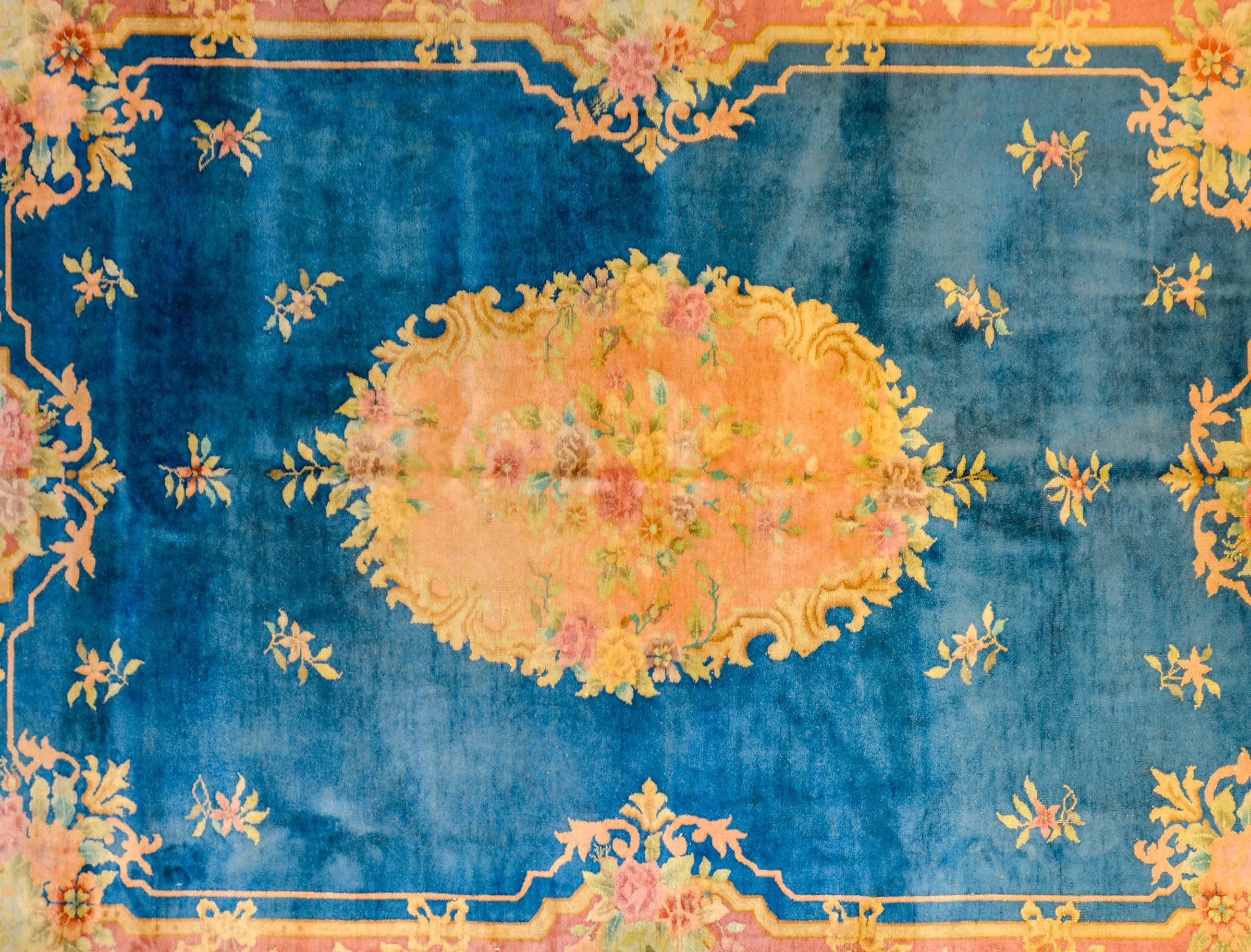 An unusual Chinese Art Deco rug with a French inspired design with a gold, rose, and violet Baroque styled floral medallion on a deep indigo field surrounded by a matching Baroque border with similar floral pattern.