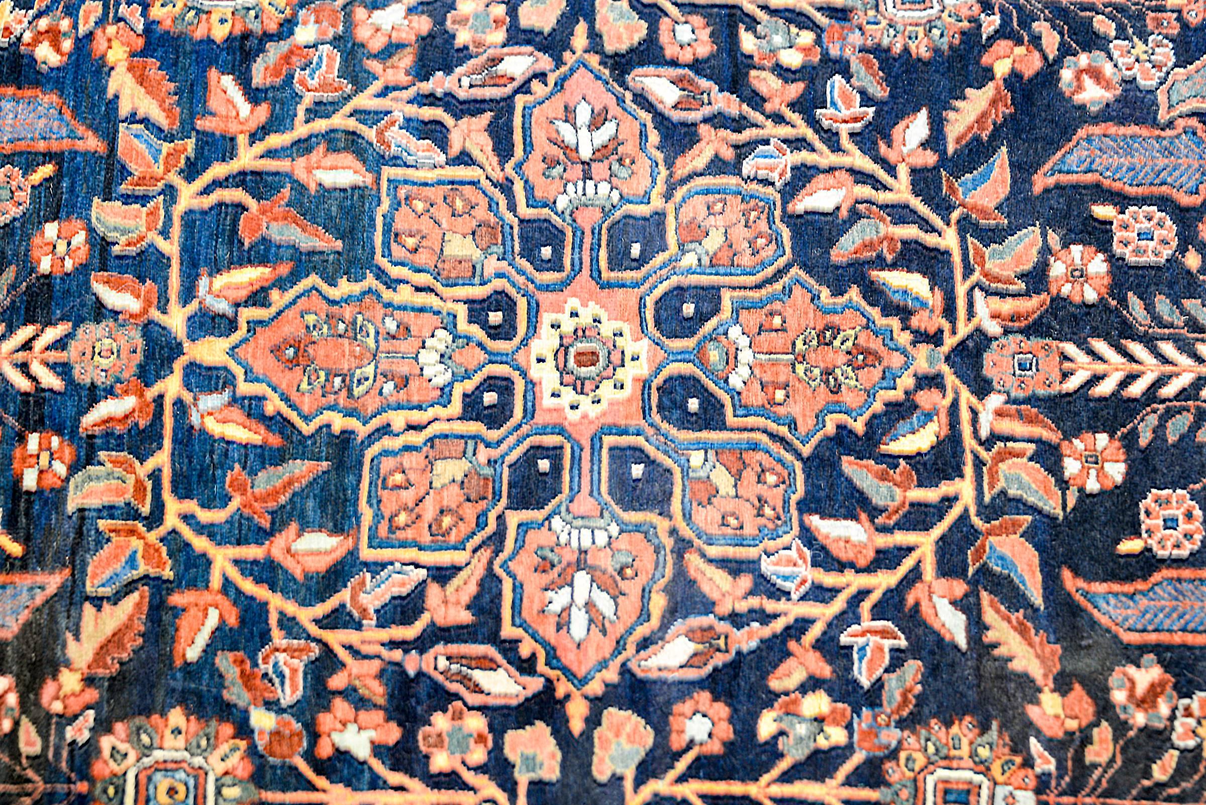 An amazing early 20th century Persian Sarouk rug with a fantastic large central lobed coral and floral medallion amidst an indigo field of flowering branches and mirrored trees-of-life at each end. The border is beautiful with a wide central