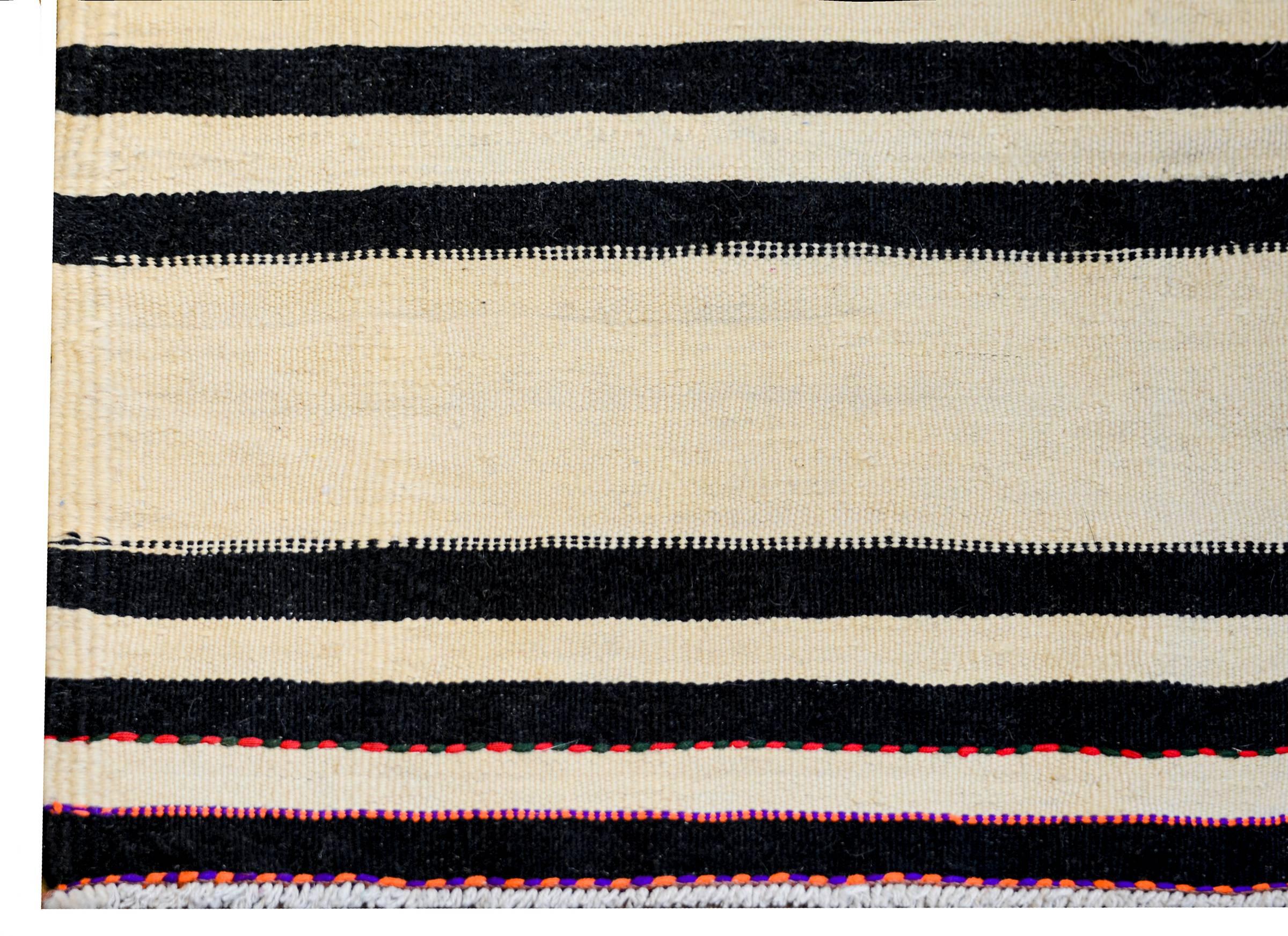 A wonderful early 20th century Persian Gabbeh Kilim runner with a bold horizontal stripe pattern with alternating black and natural wool stripes. Each black stripe is edged with a petite black and white trim pattern.