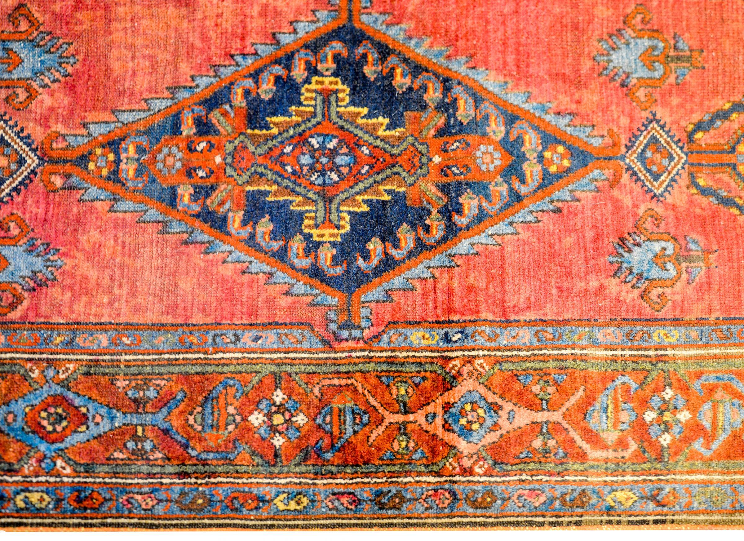 A gorgeous early 20th century Persian Malayar rug with a beautiful central diamond medallion on a brilliant crimson background. The border is wonderful, with a central stripe on stylized leaves and scrolling vines flanked by matching petite floral