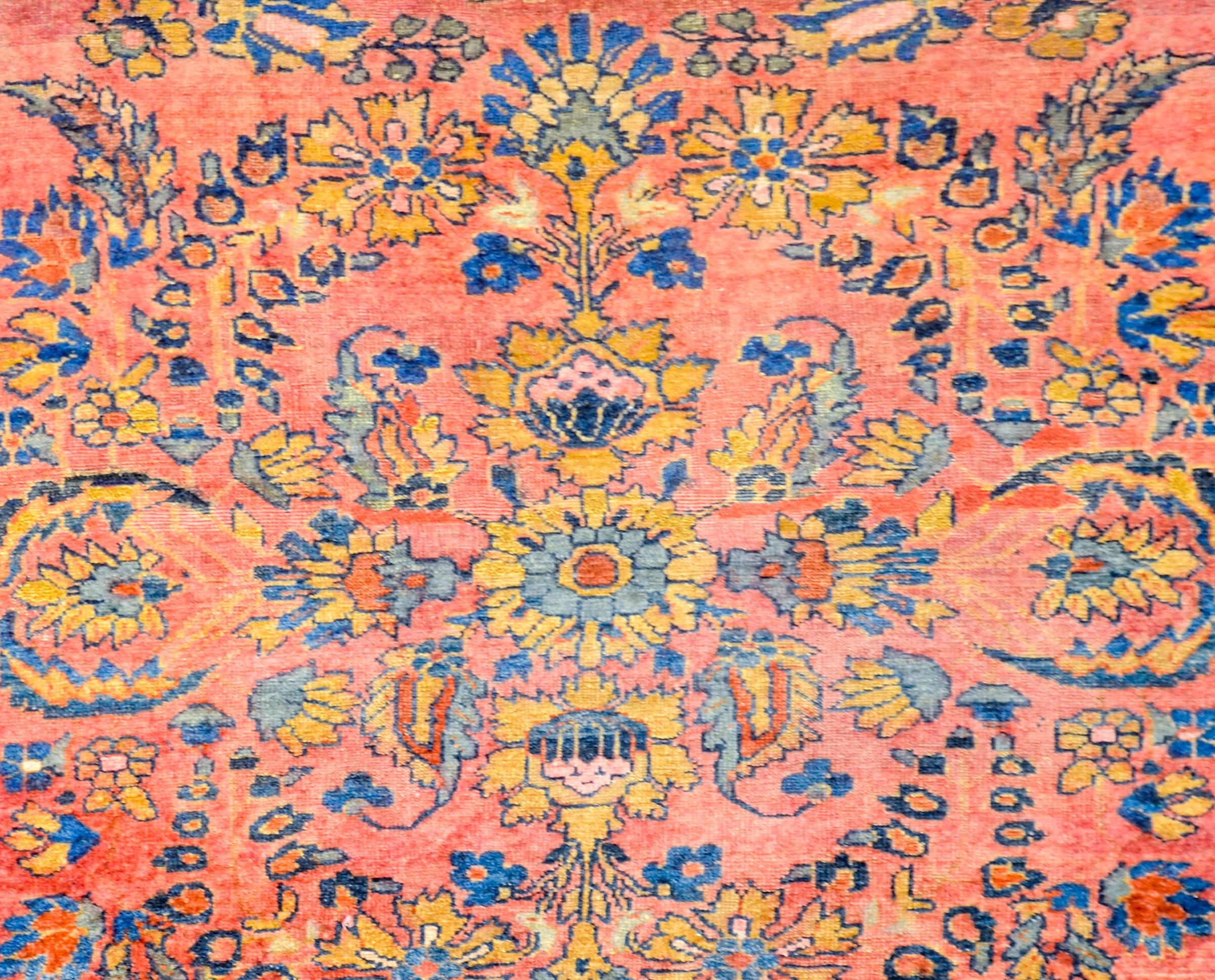 An early 20th century Persian Lilihan rug with sweet all-over floral pattern woven in indigo, orange, yellow and pink vegetable dyed wool. The border is contrasting with a large-scale floral and leaf pattern woven on a dark indigo background flanked