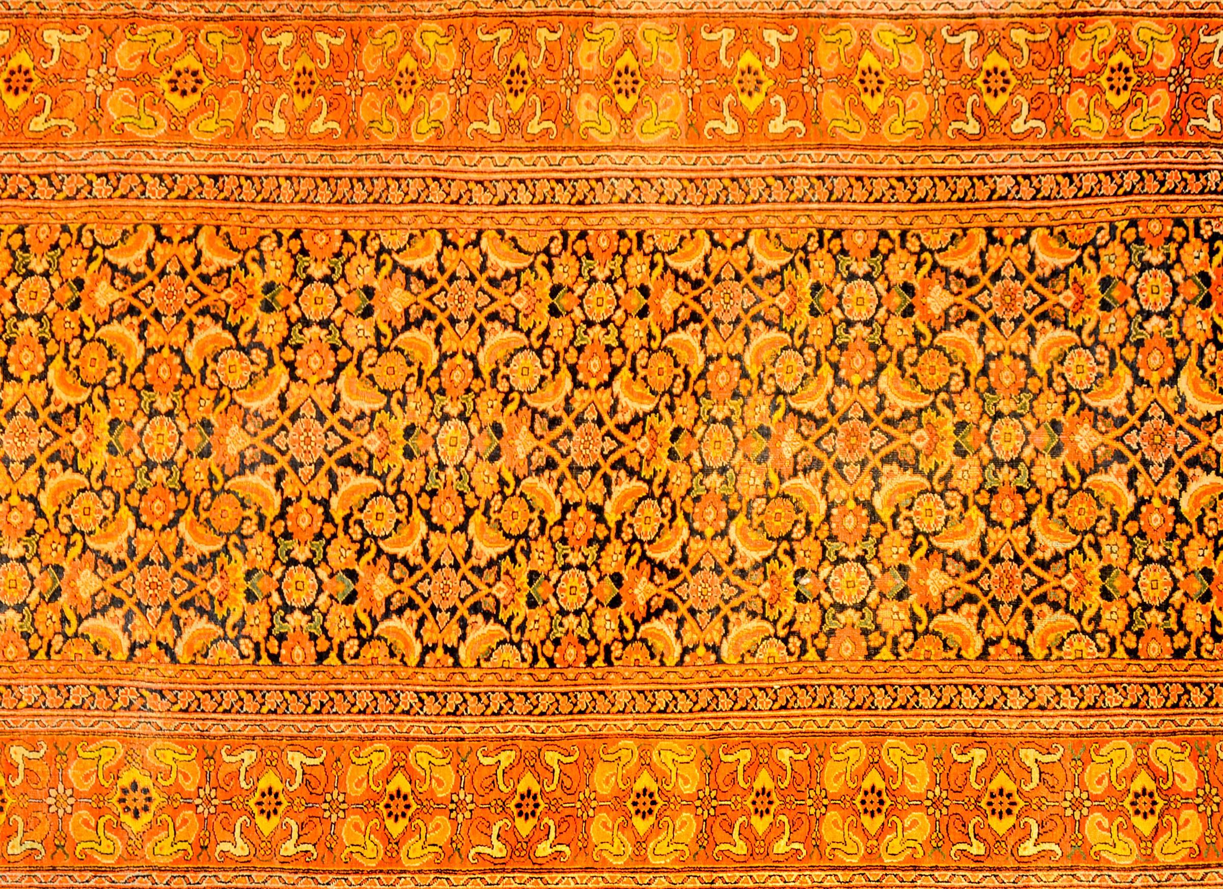 A wonderful early 20th century Persian Bidjar rug with an all-over lattice floral pattern woven in orange, crimson, gold, and indigo, on a beautiful indigo background. The border is amazing, composed of multiple floral patterned stripes.