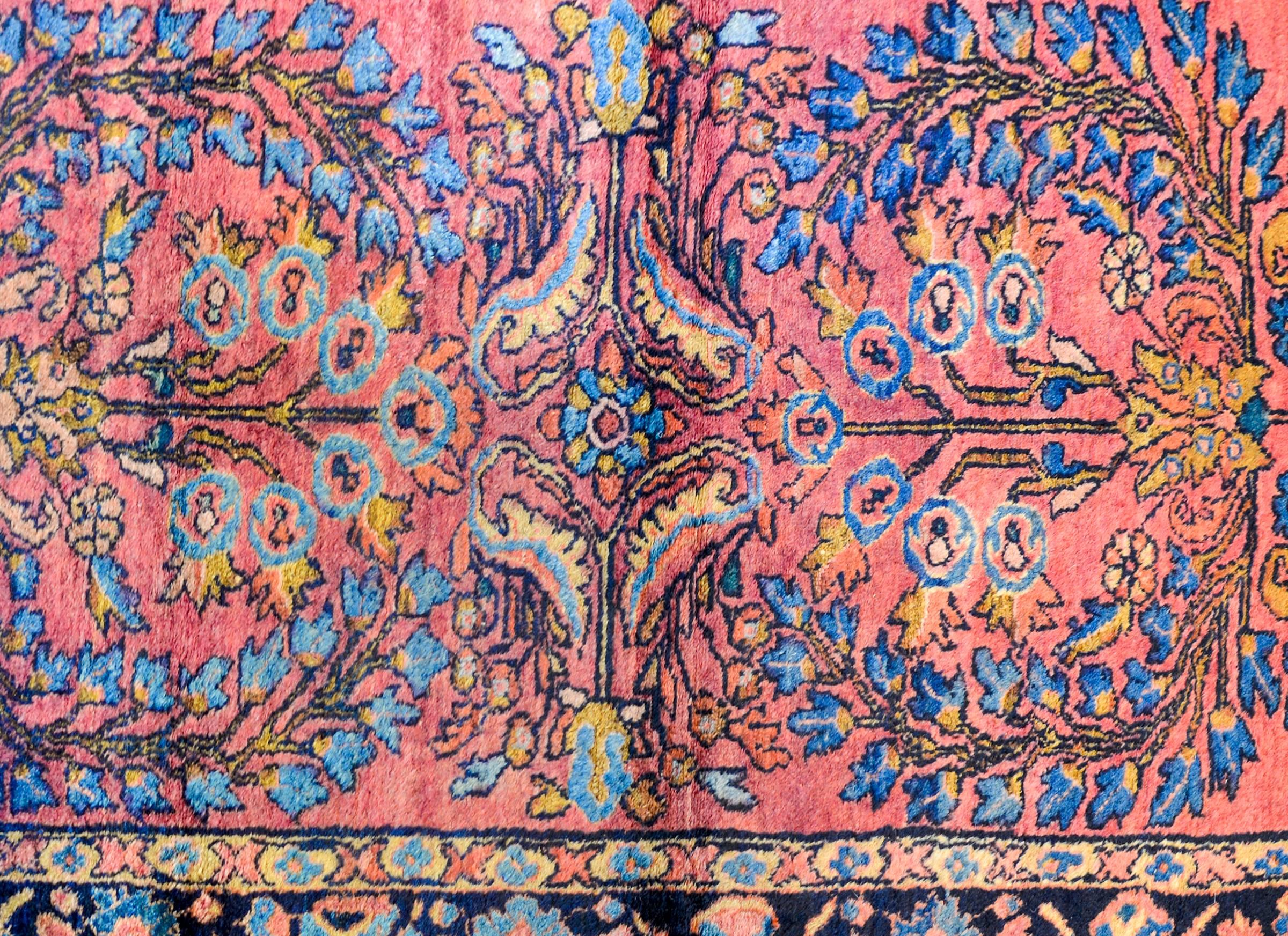 An early 20th century Persian Lilihan rug with a beautiful mirrored tree-of-life pattern woven in indigo, orange, yellow and pink vegetable dyed wool. The border is contrasting with a petite floral and leaf pattern woven on a dark indigo background.