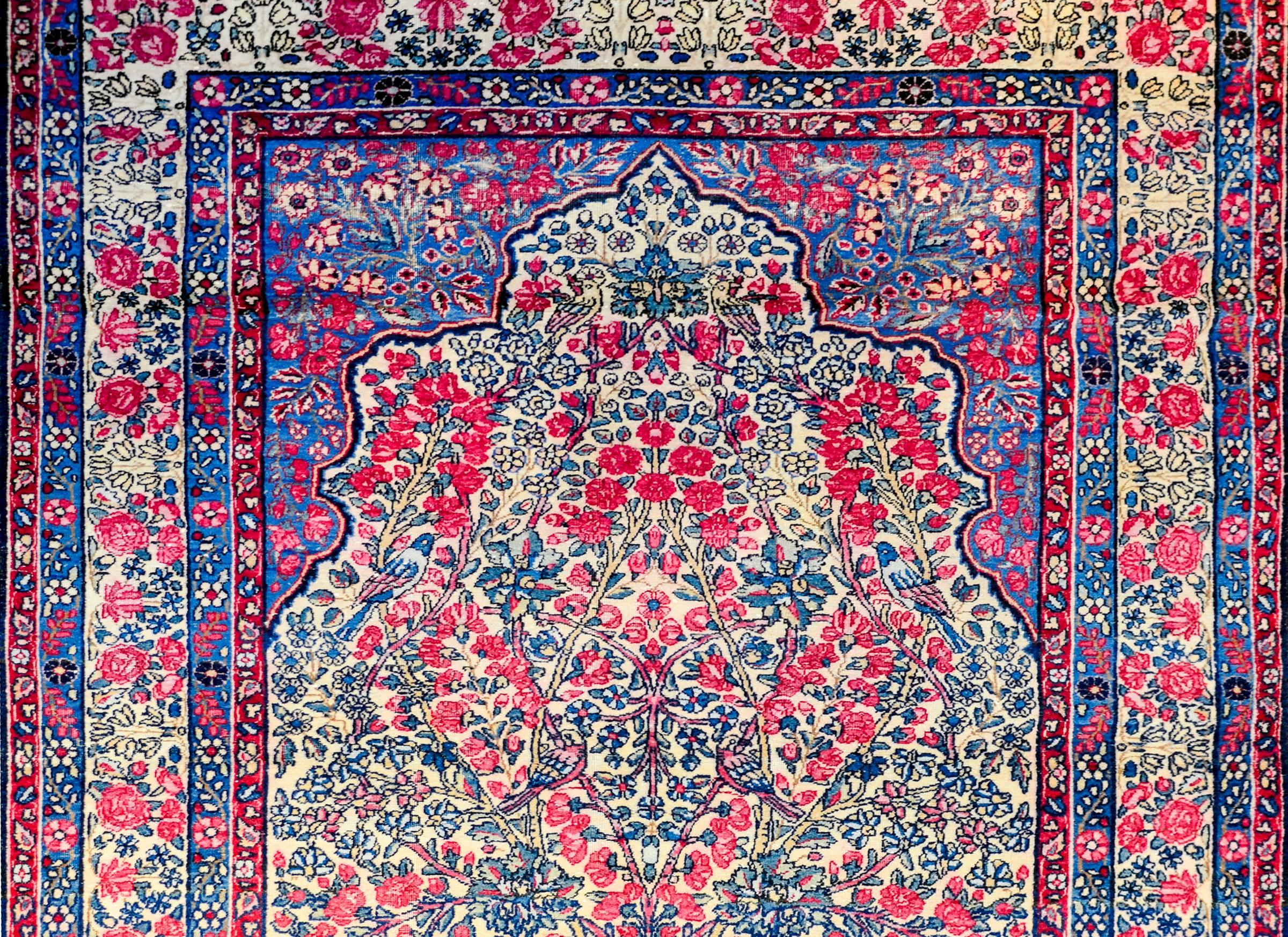 A beautiful early 20th century Persian Lavar Kirman prayer rug with a wonderful densely woven tree-of-life containing myriad variety blossoming flowers amidst a field. The border is typical, with a densely woven floral and leaf pattern, flanked by
