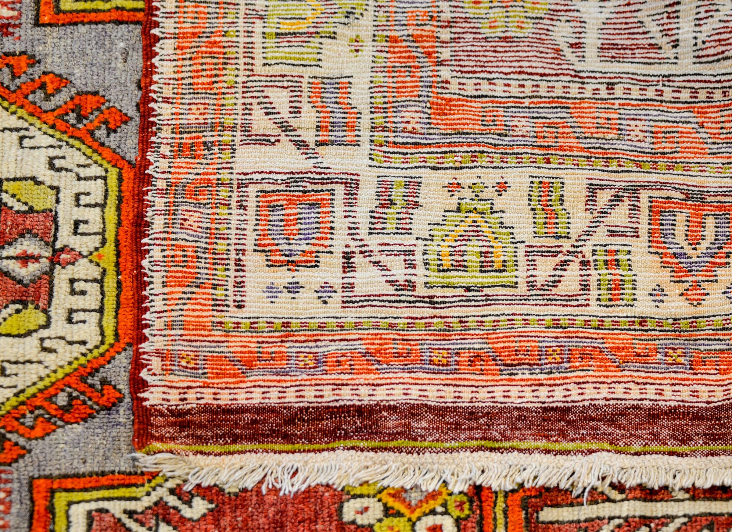 A wonderful vintage Turkish Konya rug a tribal pattern of diamond medallions woven in brilliant crimson, gold, orange, and white vegetable dyed wool, surrounded by similarly patterned and colored borders.