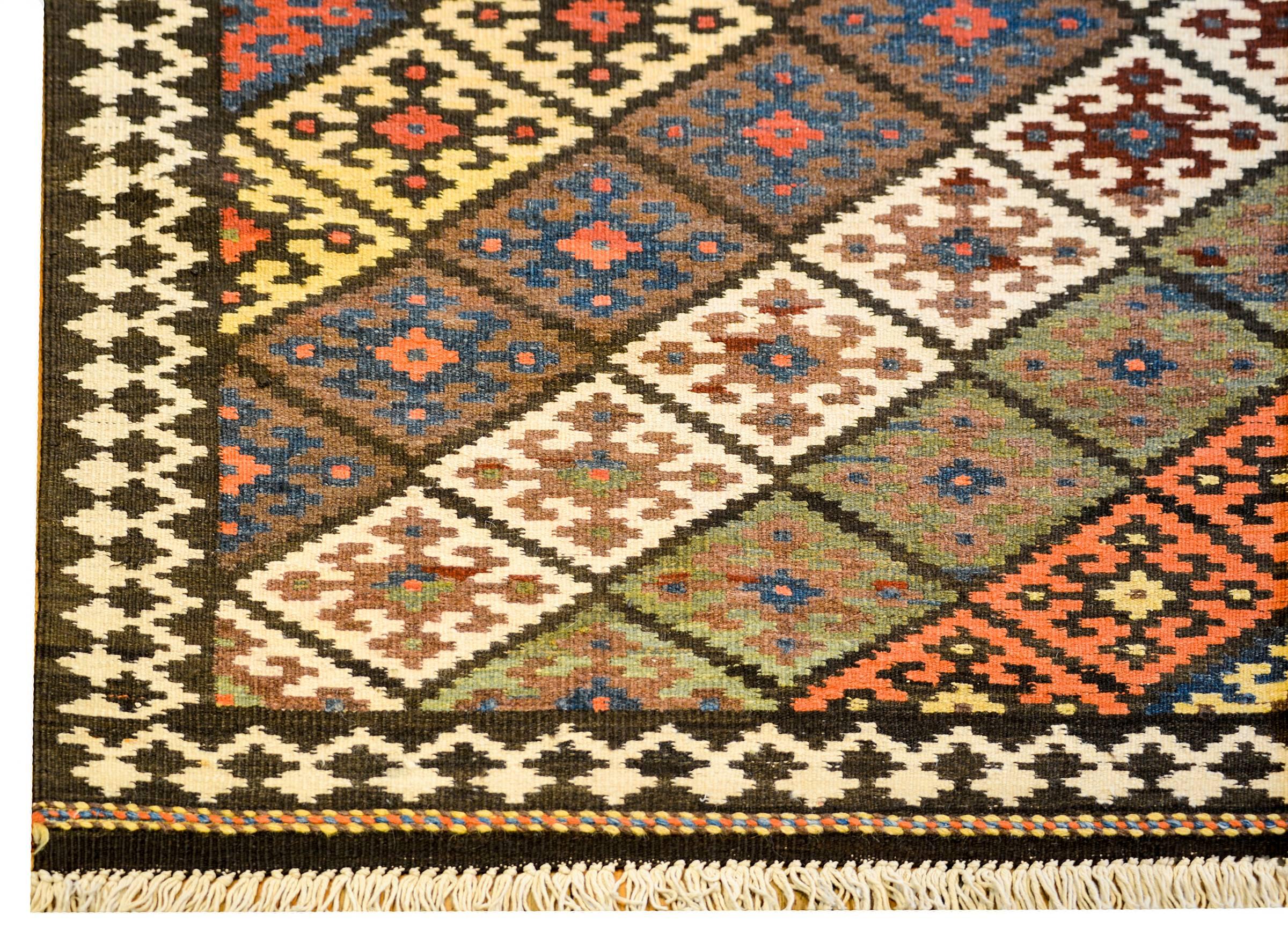 A mid-20th century Persian Saveh Kilim runner with a beautiful all-over diamond pattern of diamonds each with a geometric pattern, all woven in crimson, green, salmon, and grey vegetable dyed wool.