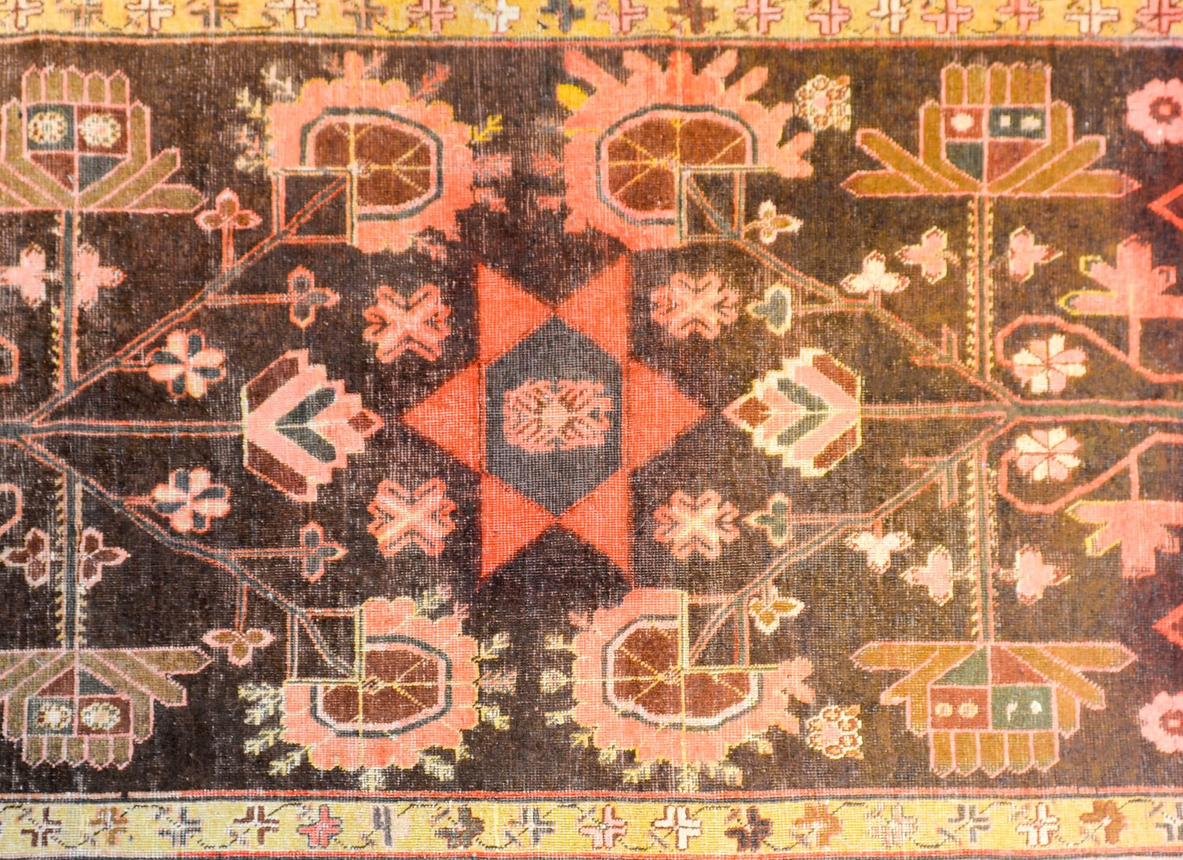 An unusual early 20th Century Central Asian Khotan rug with a wonderful pattern containing five Stars of David, amidst a field of mirrored trees-of-life, all woven in crimson, gold, pink, and grey colored wool, on a natural brown colored background.