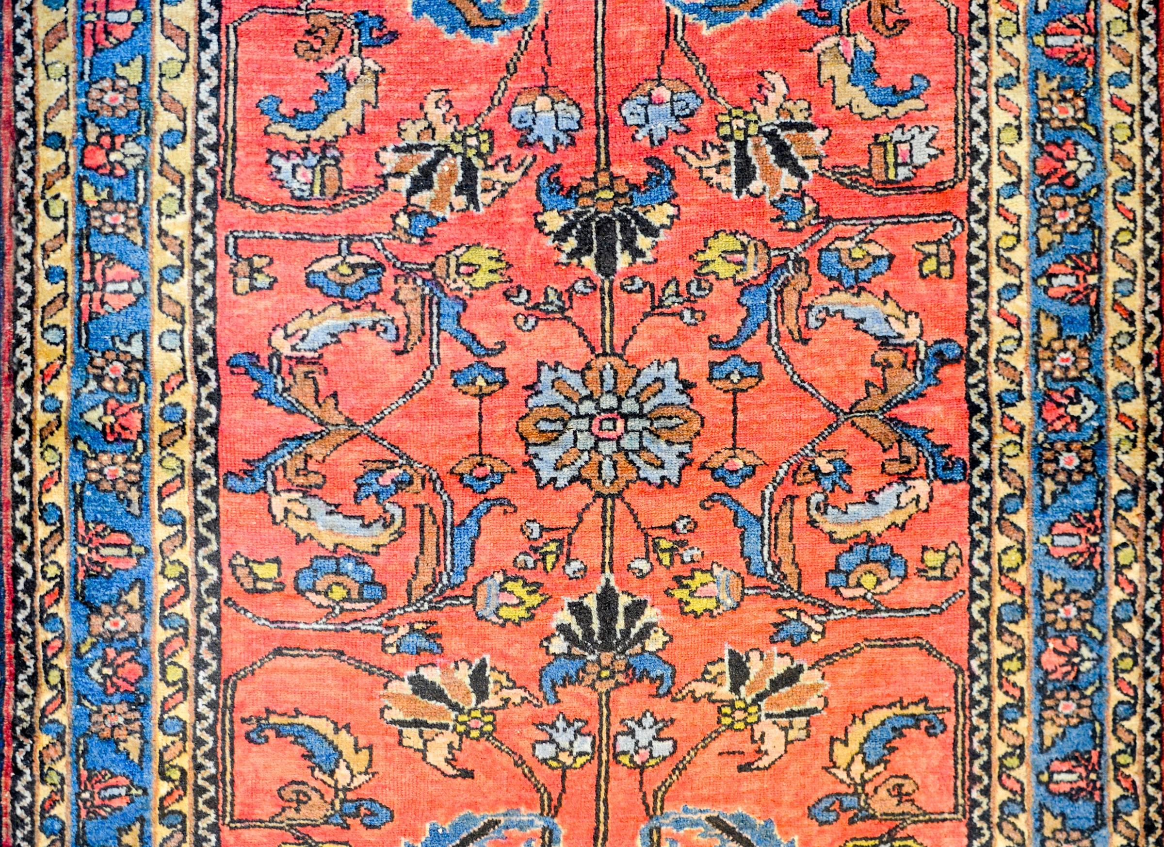 An early 20th century Persian Lilihan rug with a beautiful mirrored tree-of-life pattern woven in indigo, orange, yellow and pink vegetable dyed wool on a salmon colored background. The border is contrasting with a petite floral and leaf pattern