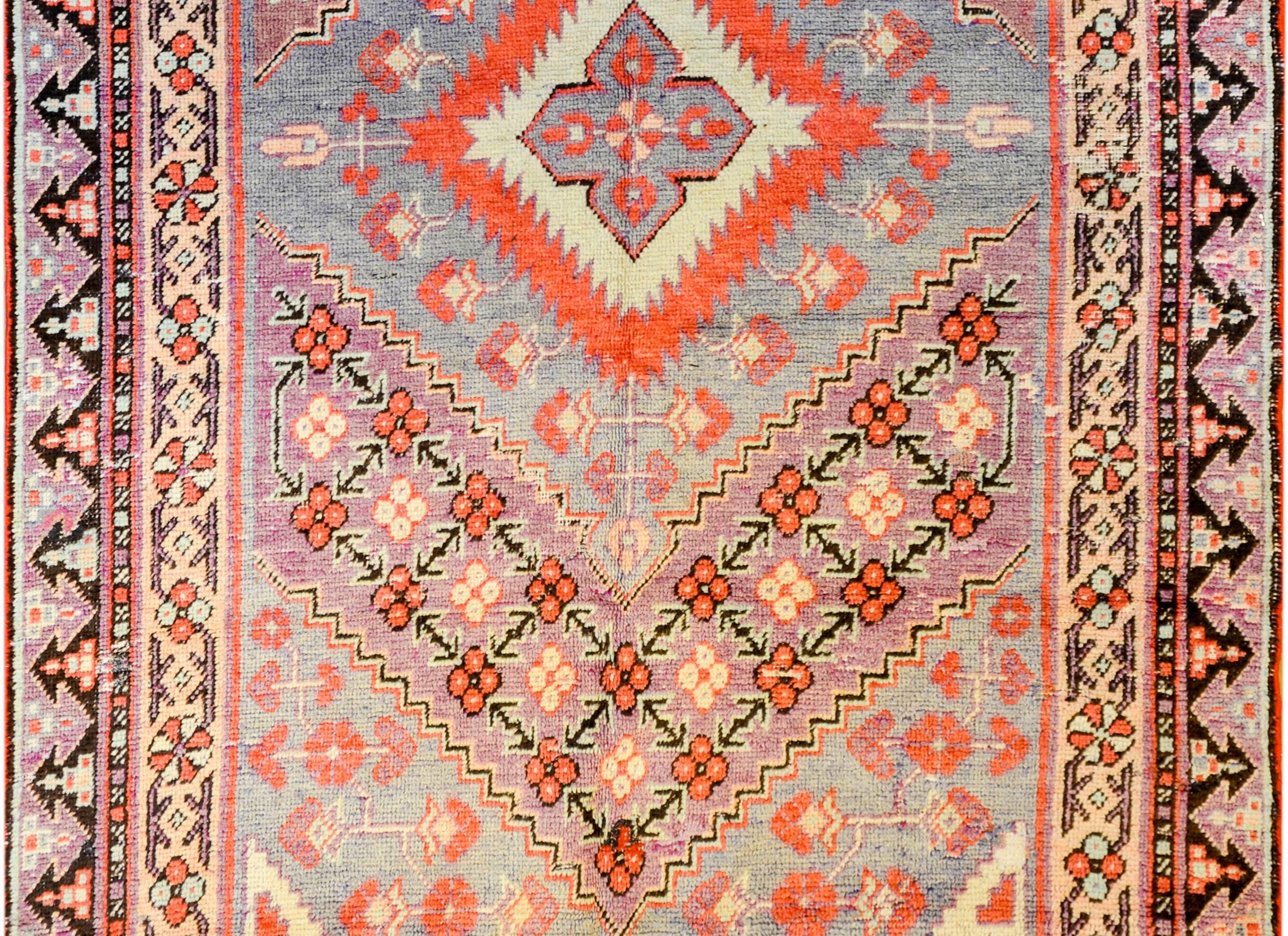 An early 20th century Central Asian Samarkand rug with large diamond and floral medallion, amidst a field of flowers, surrounded by a complementary floral border, all woven in crimson, lavender, indigo, and gold vegetable dyed colored wool.