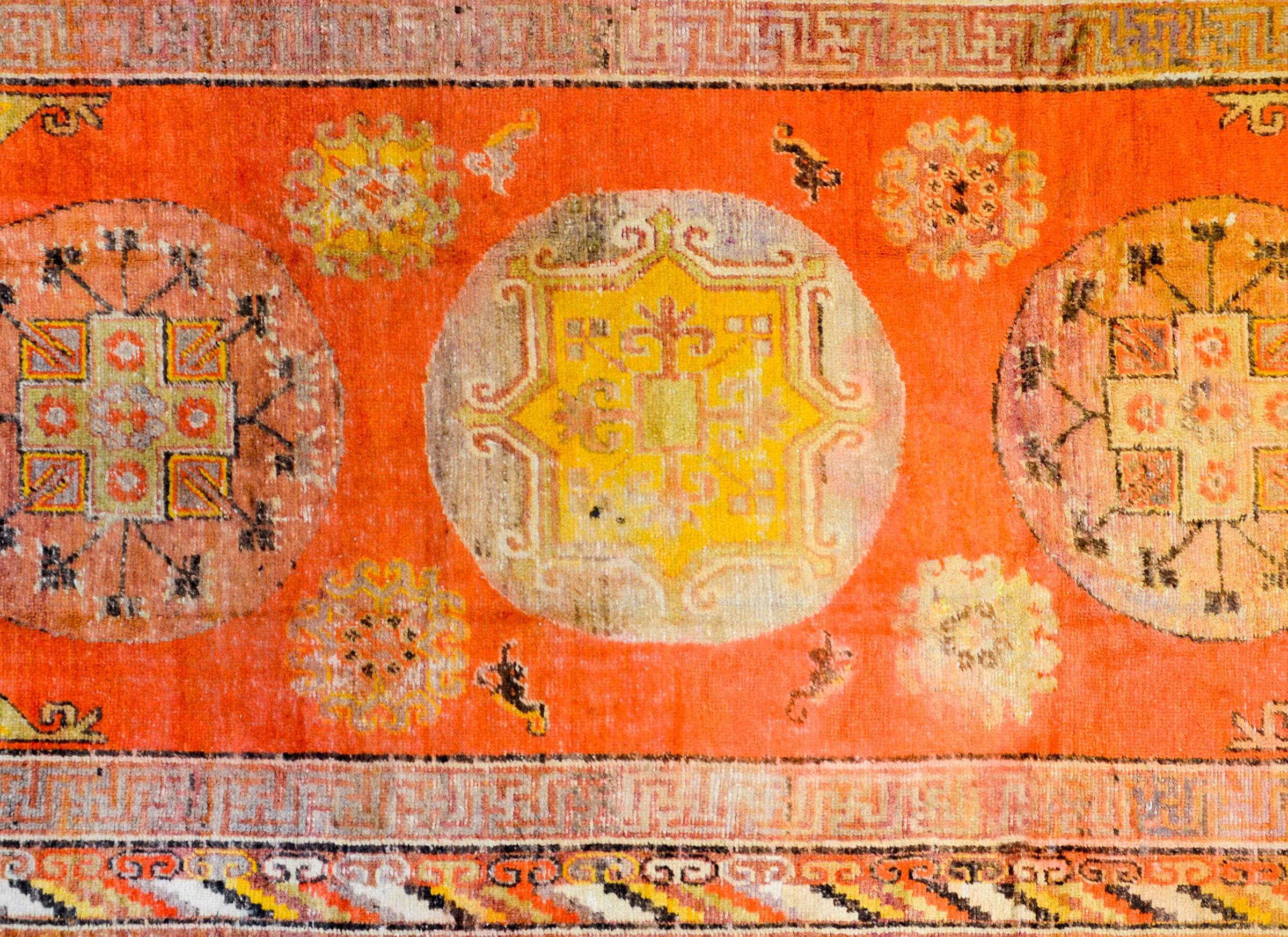 An amazing early 20th century Samarkand rug with three large circular medallions amidst an intense orange field of more medallions with floral and geometric patterns, surrounded by two distinct borders, an inner "meandering motif", and an