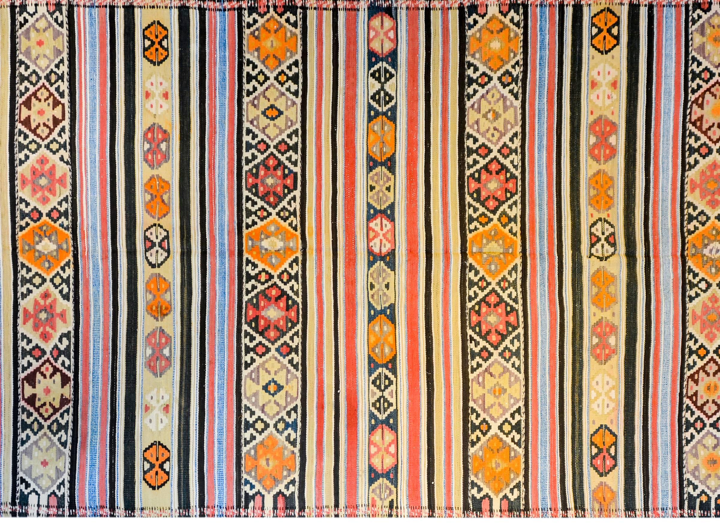 A wonderful mid-20th century Persian Zarand Kilim runner with alternating boldly multicolored stripes of geometric and stylized floral design, woven in crimson, orange, indigo, black, and coral colored wool.