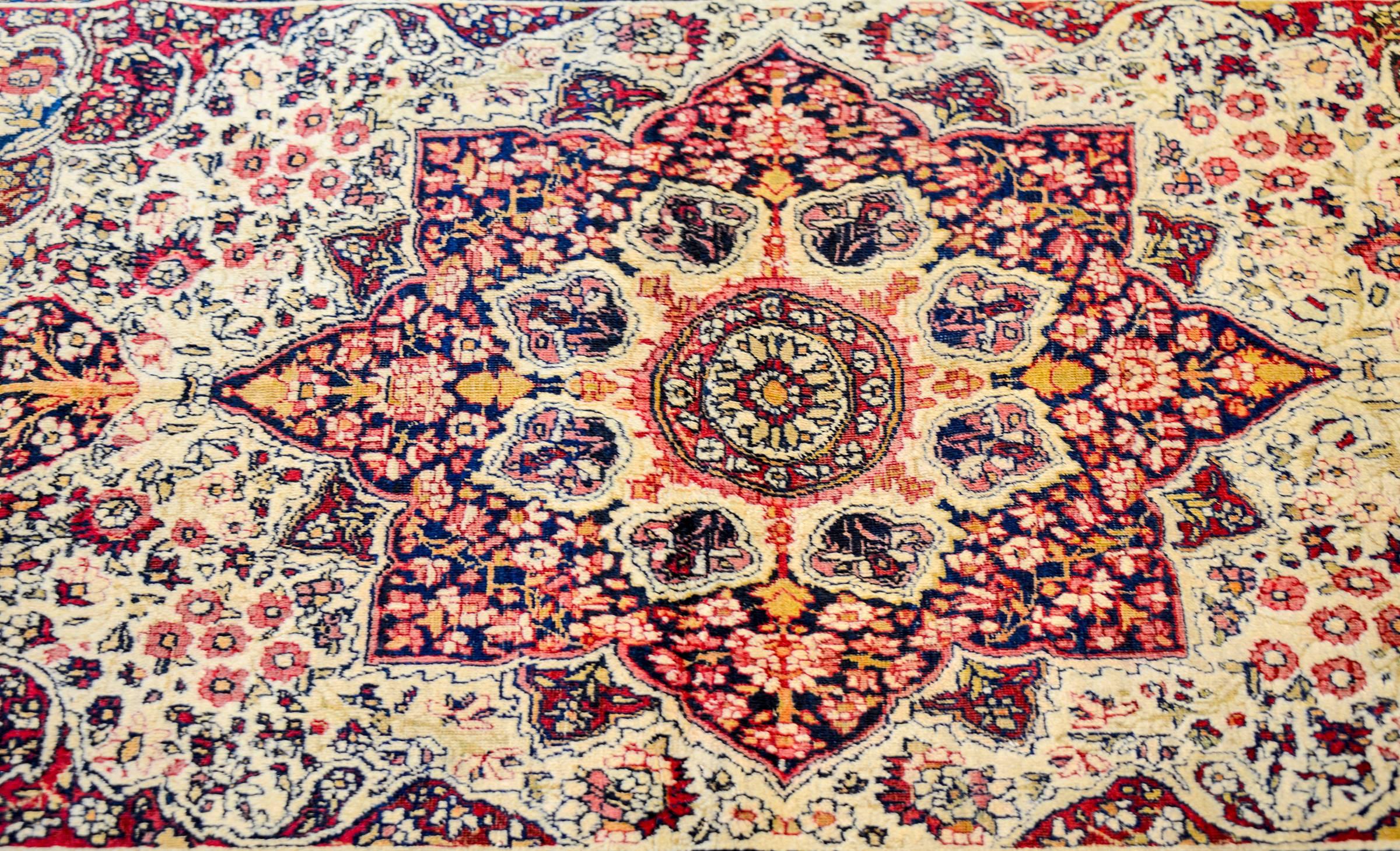 Un incredibile tappeto persiano Lavar Kirman della fine del XIX secolo con un bellissimo medaglione floreale centrale in mezzo a un campo intensamente intrecciato di fiori e viti. Il bordo è complesso, composto da un'ampia striscia centrale a fiori