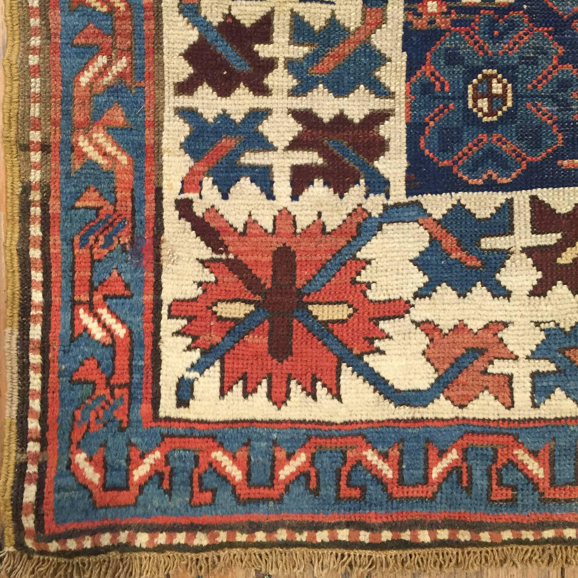 A wonderful late 19th century Persian Shriven runner with six multicolored diamond medallions on an indigo field, surrounded by a large-scale tribal floral border woven in indigo and crimson hues on a white background and a wonderful red scrolling