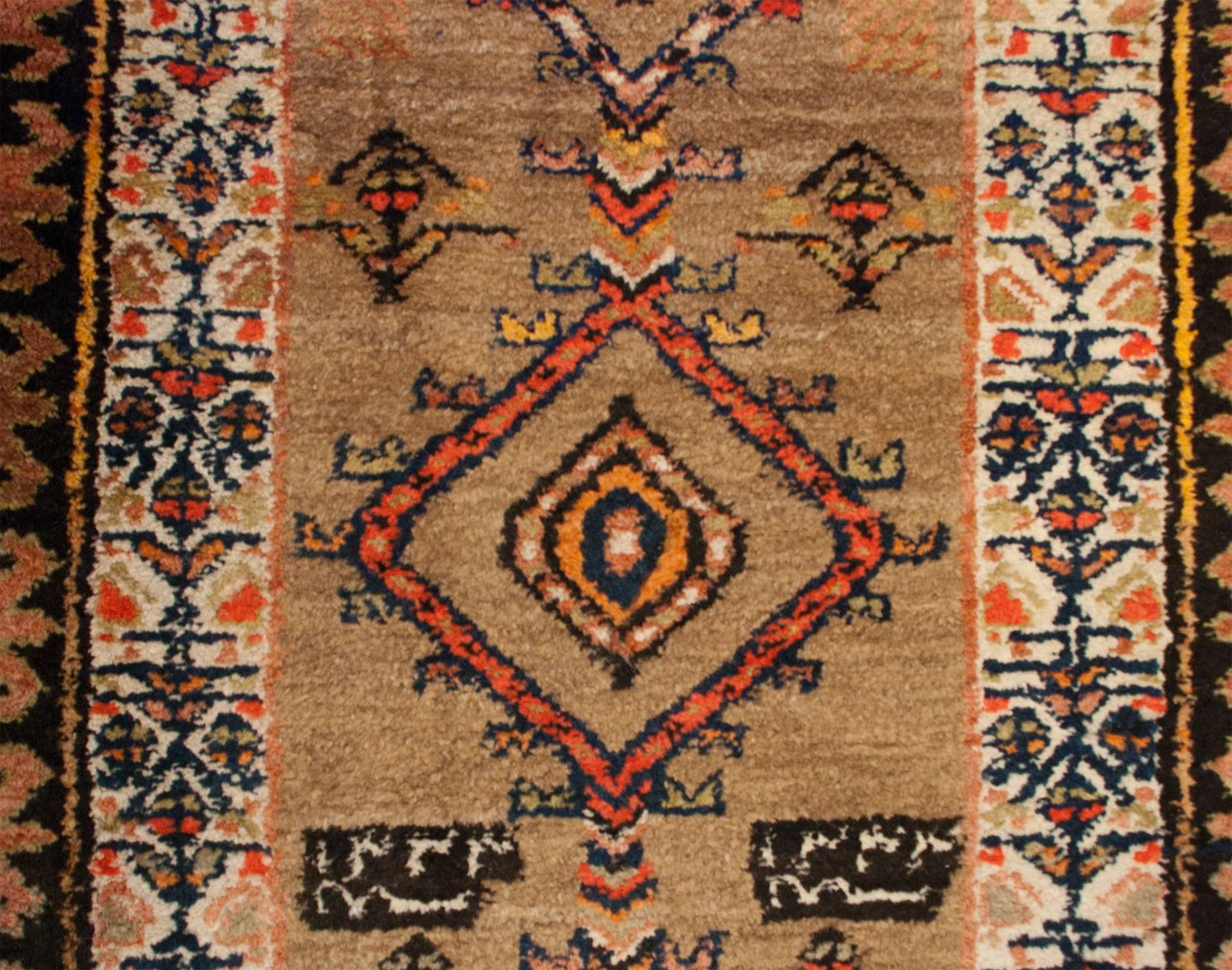 An early 20th century Persian Serab runner with multiple diamond and floral medallions on an natural, undyed, camel hair background, surrounded by a wonderful, graphic, red and brown and floral border.