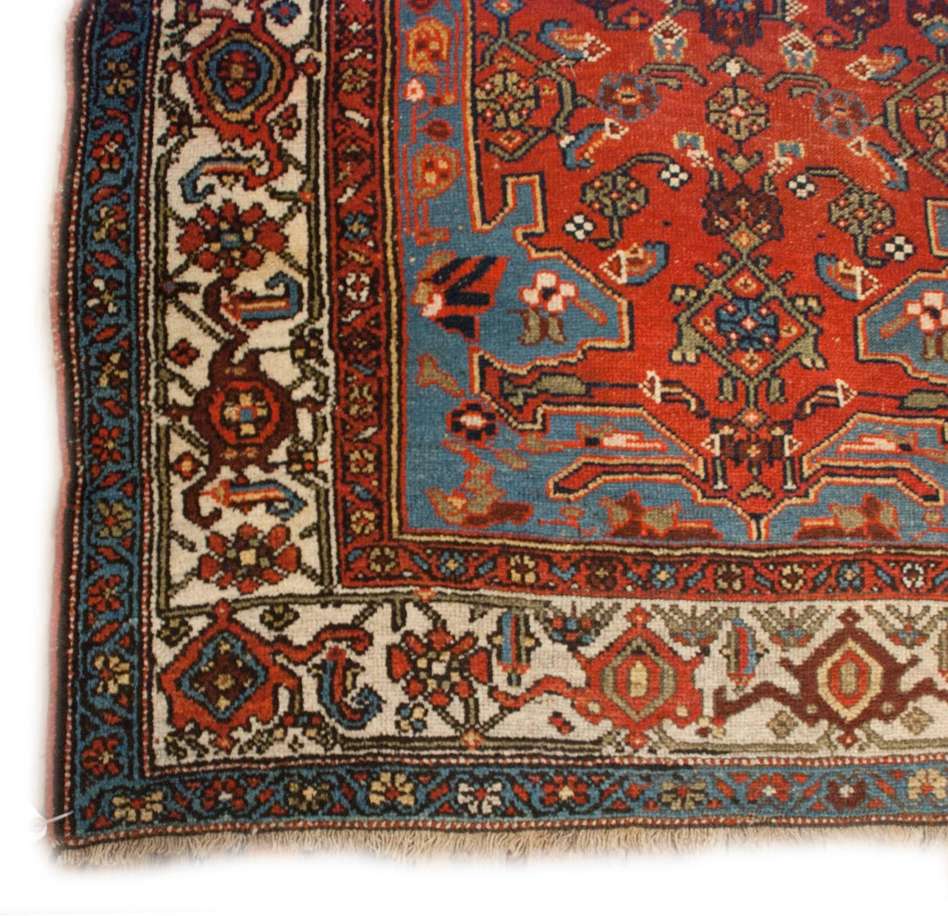 A gorgeous late 19th century Persian Bidjar runner with a wonderful multicolored field of stylized flowers and leaves on a rich crimson background, with a large asymmetrical indigo medallion that mirrors the ends which fades from crimson to indigo.