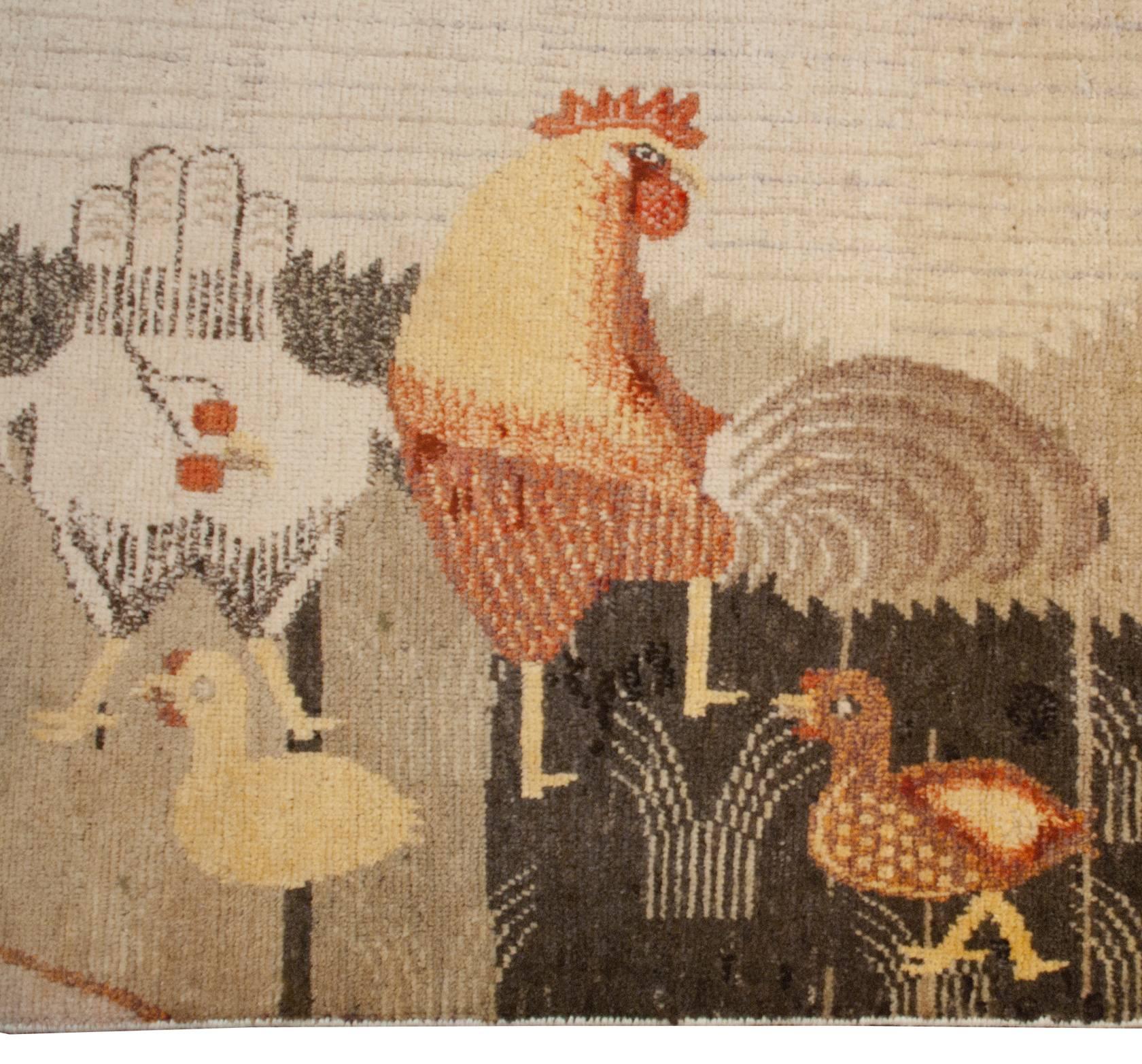 A wonderfully whimsical mid-20th century central Asian pictorial Khotan rug with a bucolic scene depicting several roosters, hens, and chicks in the foreground feeding amongst the reeds at the edge of a river, with two farmhouses in the background