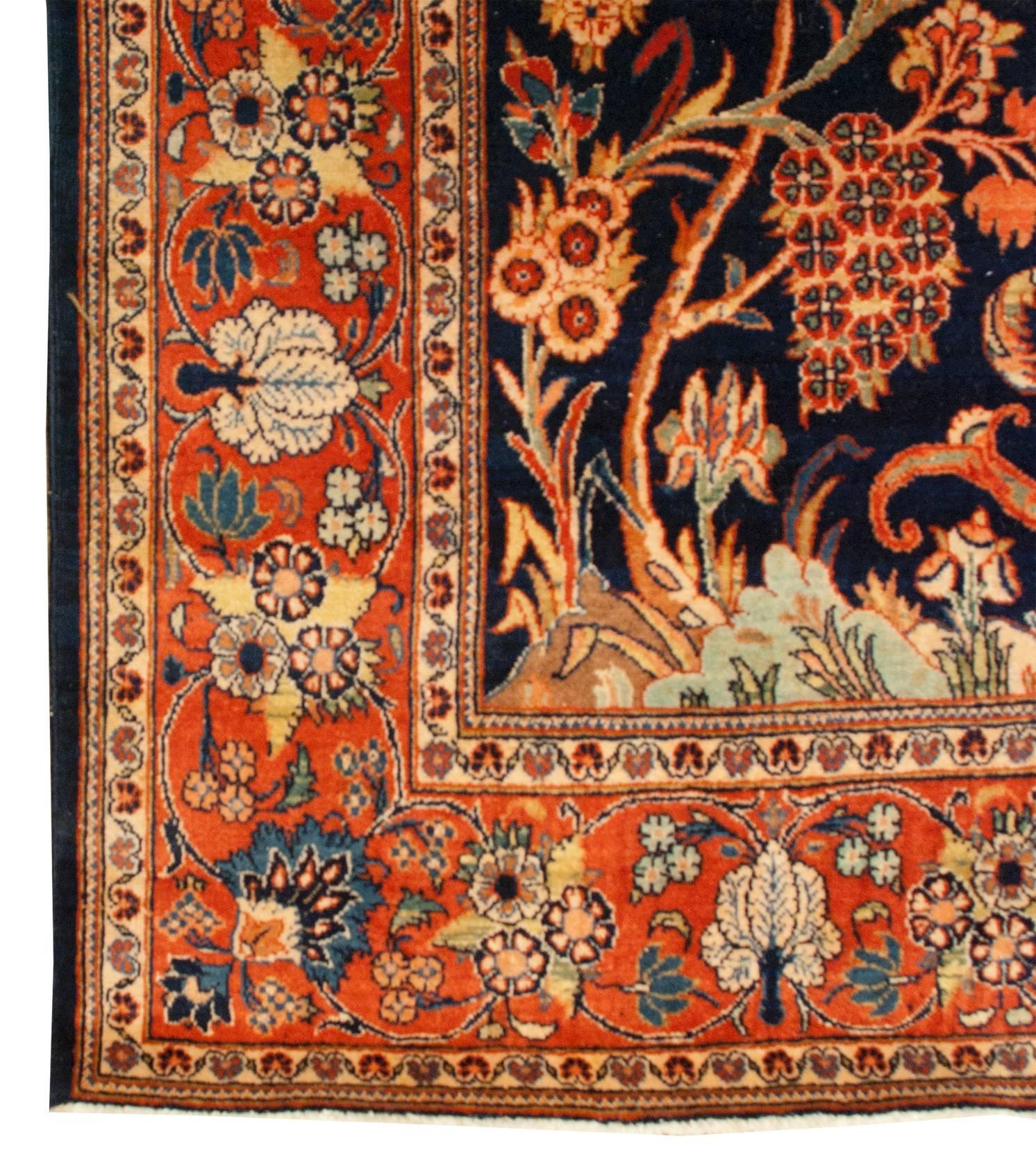 A superb early 20th century Persian Kashan prayer rug with a skillfully woven design of a vase, immensely potted with myriad multicolored flowers, in the center of a deep indigo background. Surrounding the vase are real trees, dripping with