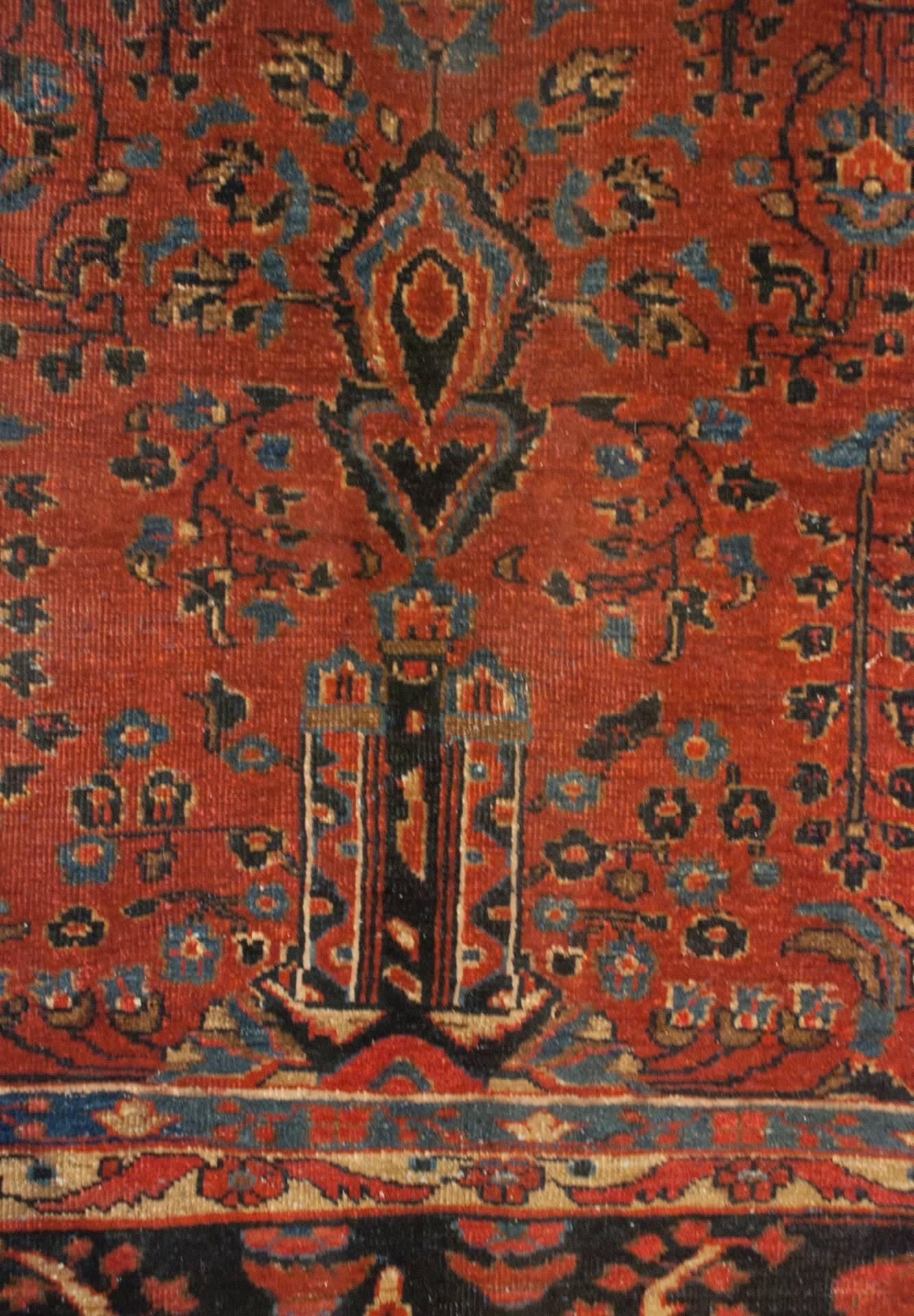 An early 20th century Persian Tabriz rug with a unique all-over multi-colored tree-of-life pattern with flowers, vines, and trees woven in dark and light indigo, and natural un-dyed wool, on a wonderful crimson background. The wide border is