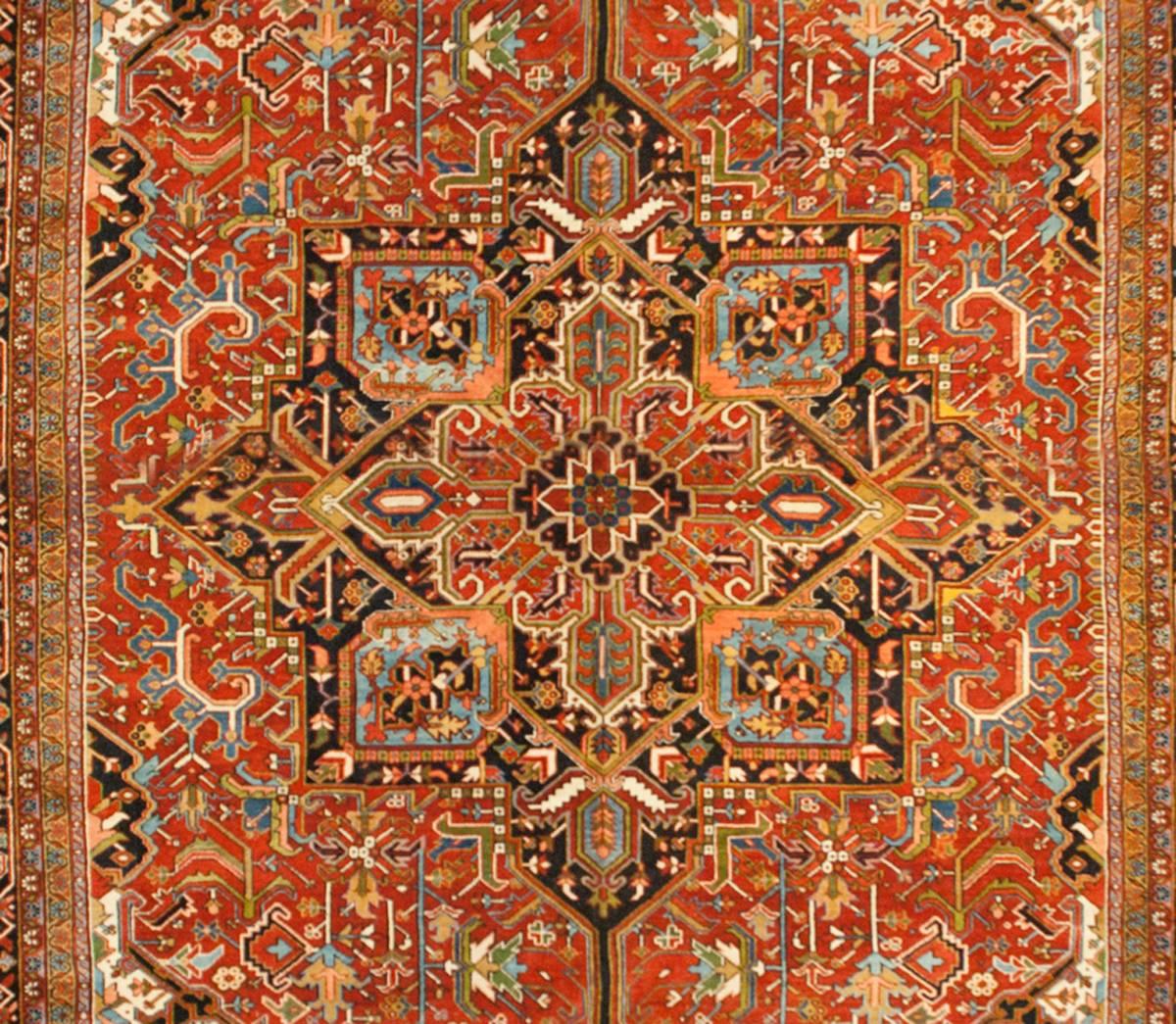 A wonderfully bold early 20th century Persian Heriz rug with a large central multicolored medallion woven in richly saturated crimson, lime green, light and dark indigo, and white wool. The field is intensely woven with large and small scale