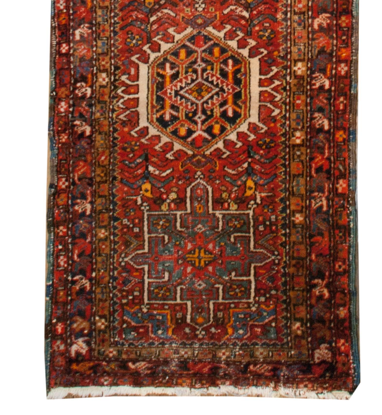 An early 20th century Persian Heriz runner with alternating geometric diamond and rectangular medallions, all with stylized decorative designs woven in brilliant crimson, indigo, gold, and white wool. The medallions are resting amidst a crimson