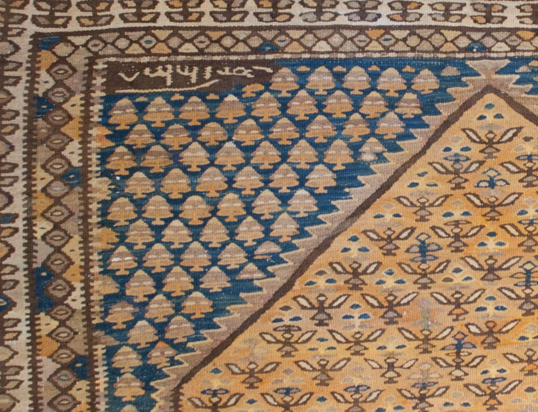 A wonderful early 20th century Persian Senneh kilim runner with a beautiful indigo diamond medallion with gold and brown circular motifs and birds, on an intricately woven field of flowers on a complementary gold background.  The border is wide,