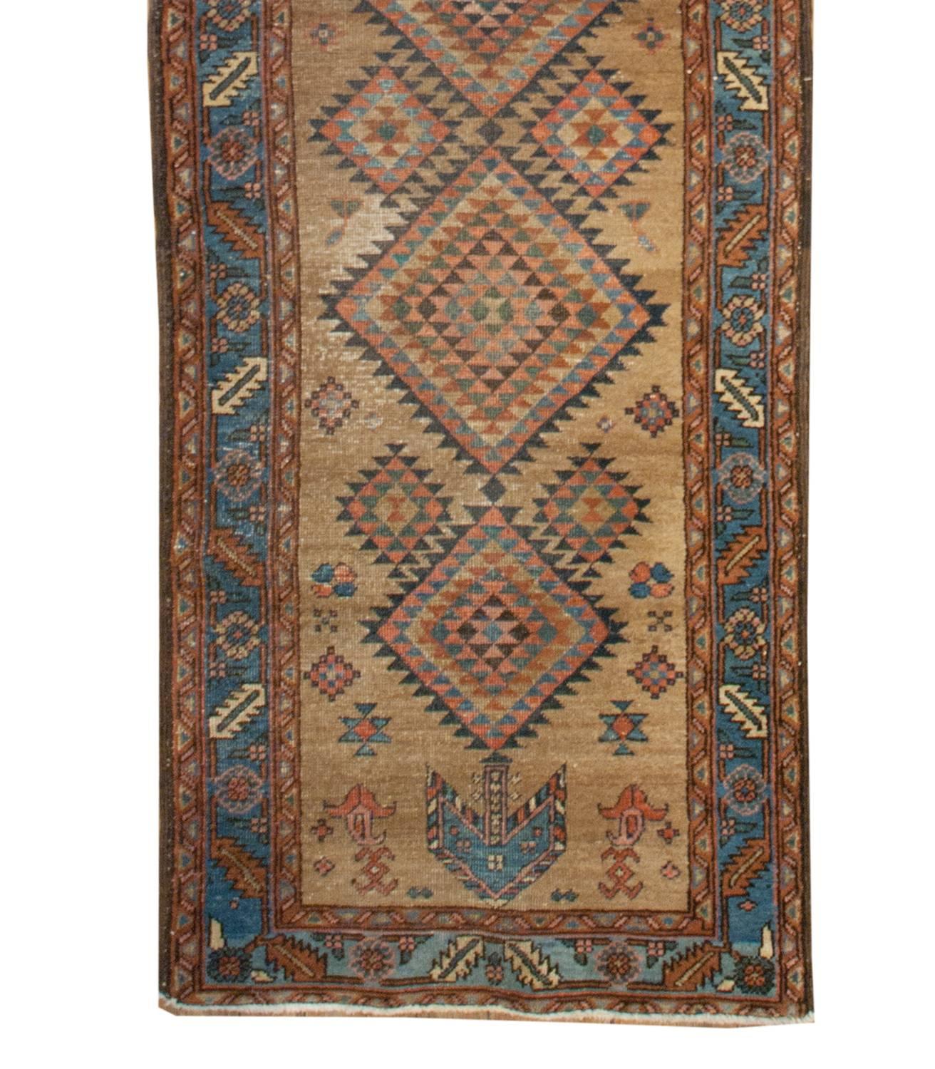 An amazing 19th century Persian Heriz runner with a wonderful pattern of multi-colored diamonds running down the center of a natural camel hair field, amidst a field of flowers.  The border is whimsical with a floral and leaf pattern on a light