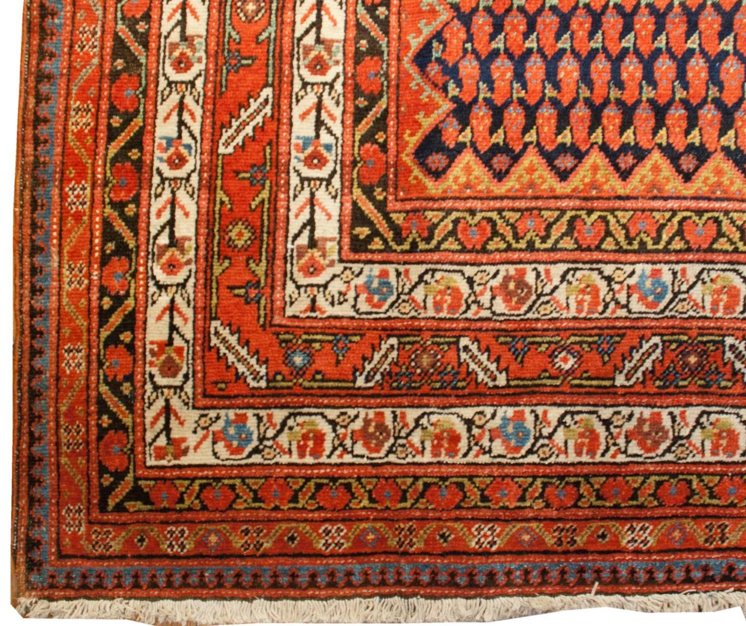 A wonderful early 20th century Persian Saraband runner with an elaborate all-over crimson and mint green paisley pattern on a dark indigo background. The border is wide, comprised of seven distinct multicolored patterns, with geometric and natural