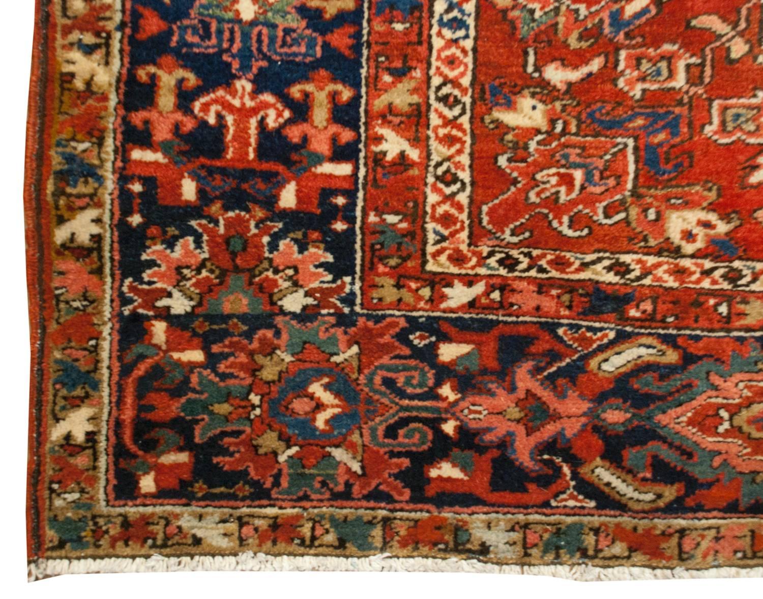 Un étonnant tapis persan Heriz du début du 20e siècle au design inhabituel, dépourvu du grand médaillon central traditionnel. Il comprend plutôt un petit médaillon indigo sur un motif floral et viticole multicolore merveilleusement tissé en miroir