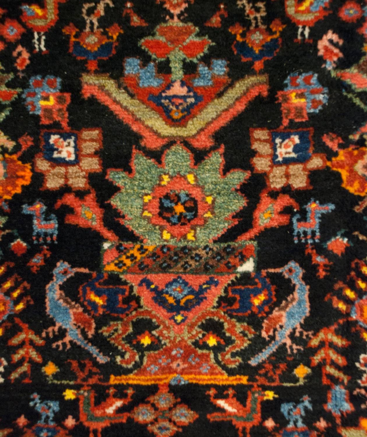 An unbelievable early 20th century Persian Bakhtiari rug with an all-over field of multicolored vases potted with myriad flowers, flanked by peacocks, ducks, and chickens all on a dark indigo background. The border is wide, comprised of a beautiful