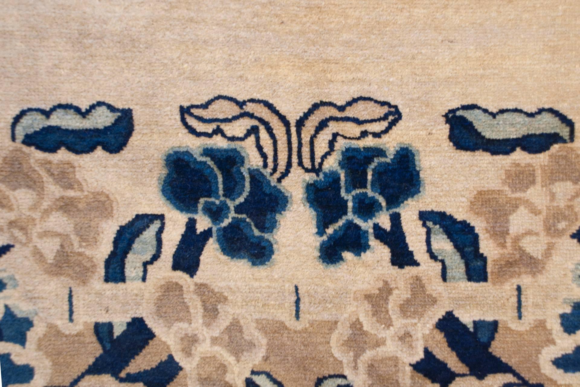 A fascinating mid-19th century Chinese Peking rug with a whimsical pattern of intertwining blossoming tree peonies with birds nestled among the branches, all woven in light and dark indigo, and undyed natural wool in cream tones. The border is