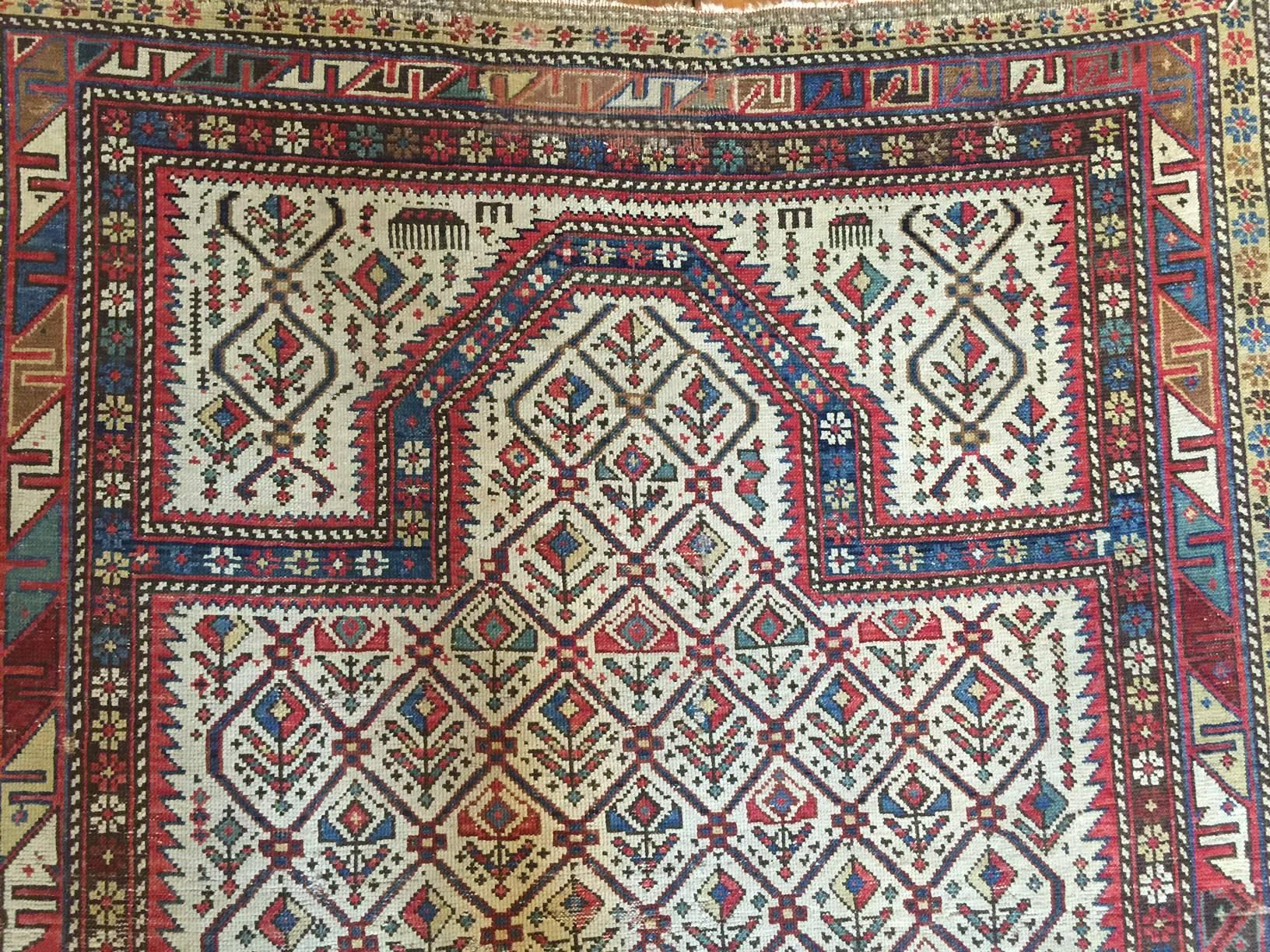A late 19th century Persian prayer rug with a sweet all-over multicolored floral pattern on a white background surrounded by two beautiful borders. One border is a petite floral pattern, and the other is a geometric 